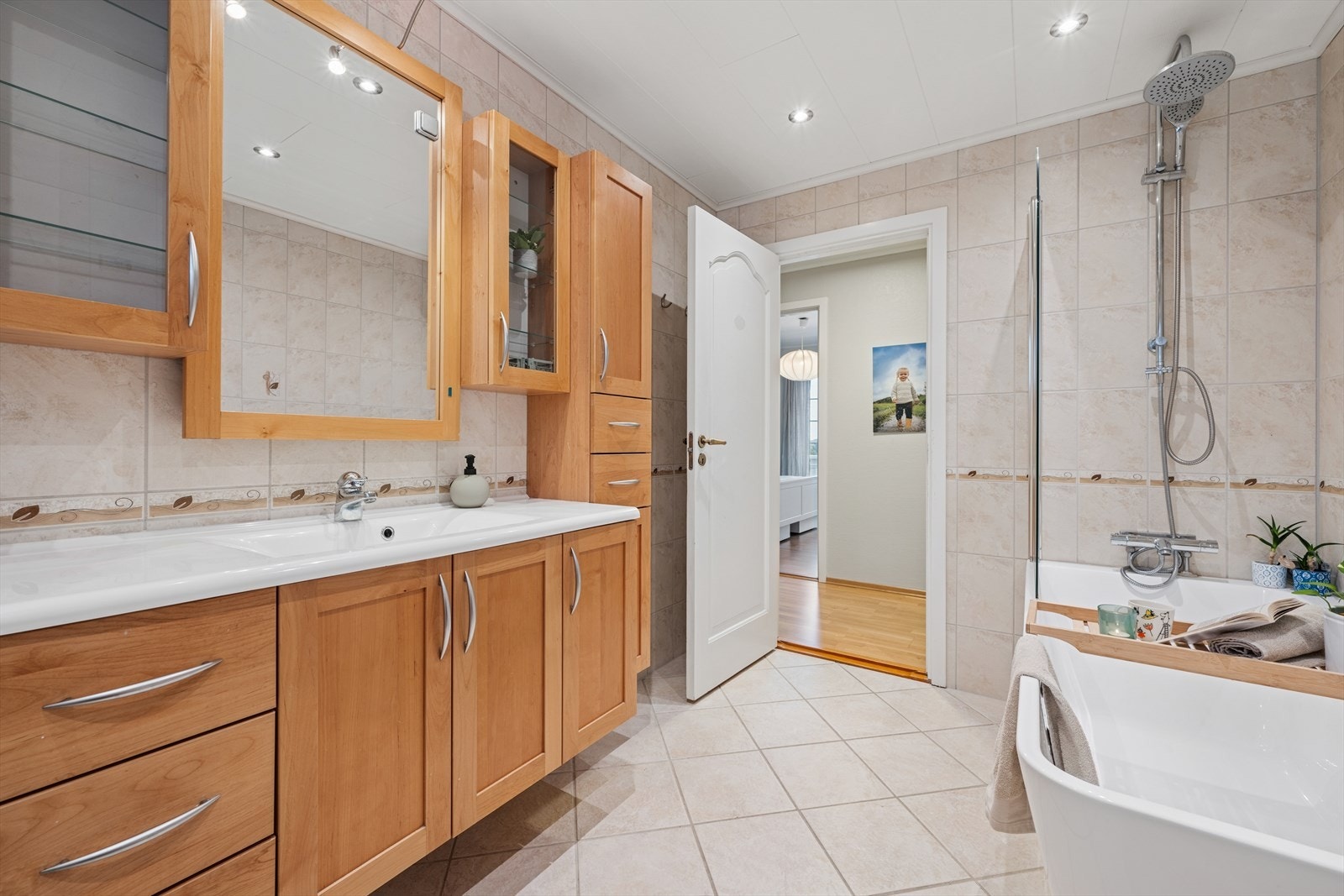 Badet har baderomsinnredning med heldekkende servant og speil på vegg, veggmontert wc og badekar. Galleribilde