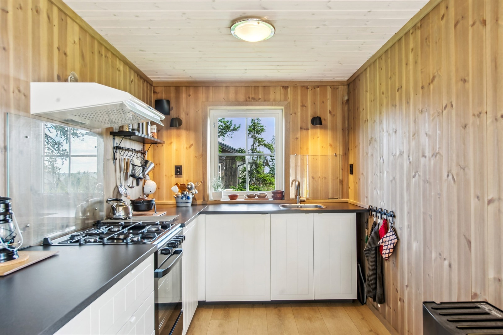 Det er montert glassplater på veggen bak kokesonen og oppvaskkummen. Frittstående gasskomfyr medfølger. Galleribilde