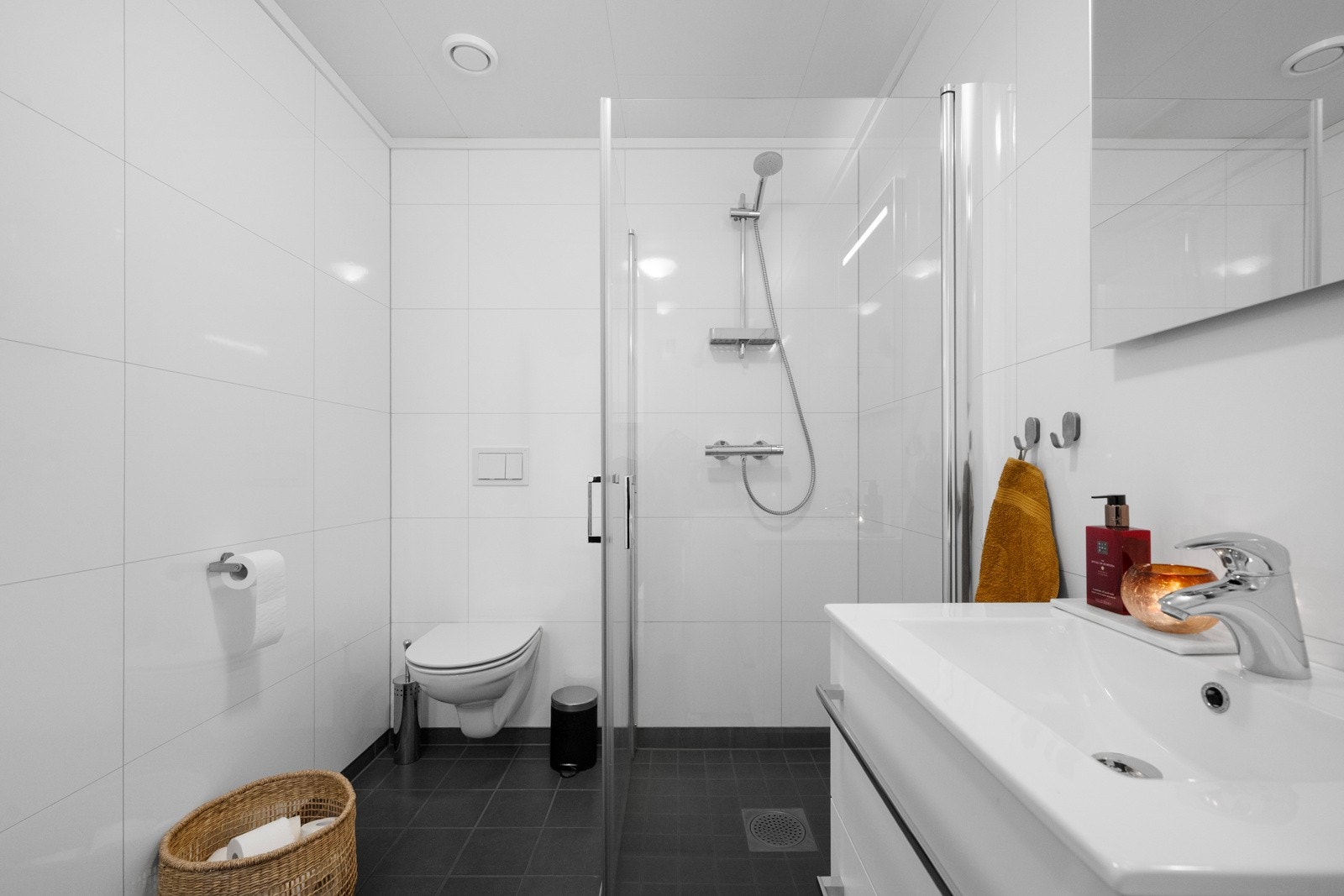 Badet er innredet med servant med skap, vegghengt WC og dusjsone med glassdører Galleribilde
