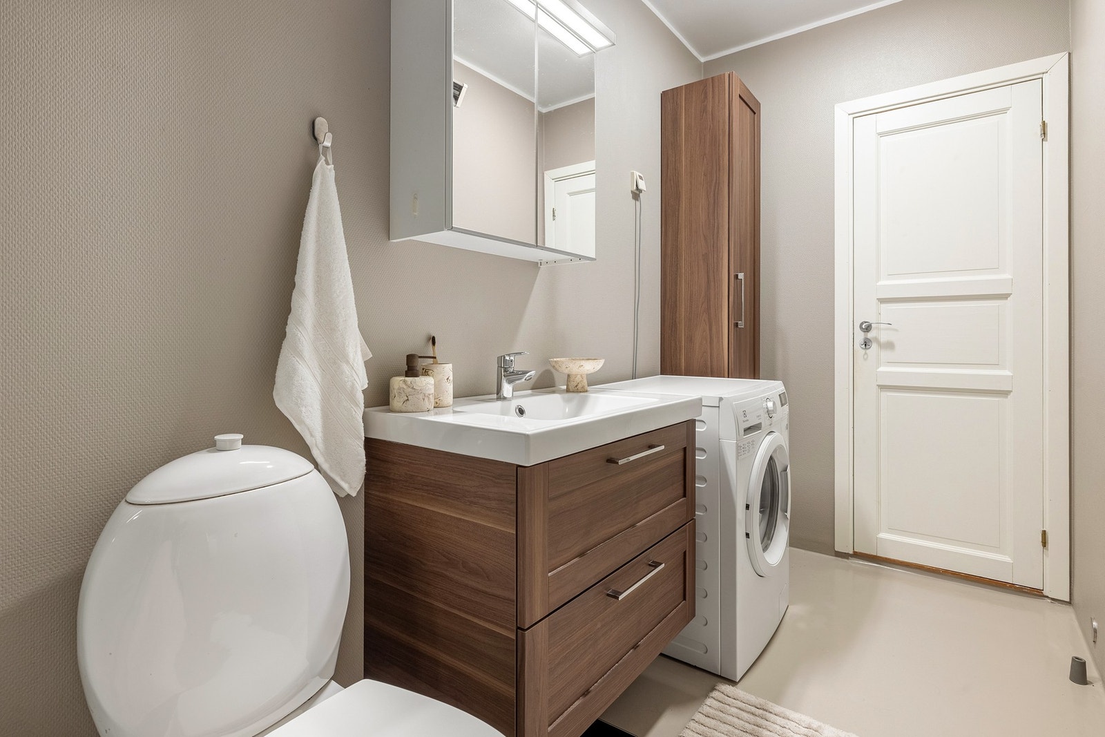 Badet er innredet med toalett, dusjkabinett og baderomsinnredning med servant, speilskap og belysning. Galleribilde