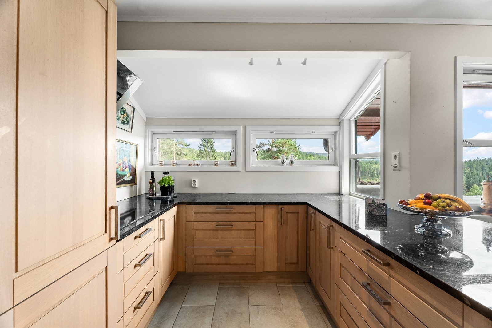 Det er godt med skap- og benkeplass i det lyse kjøkkenet. Benkeplate i stein(Larvikitt?- Labrador?) Galleribilde