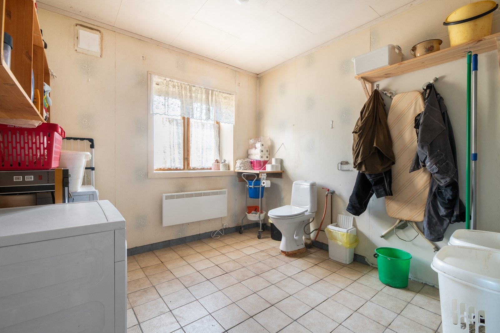 Stort, kombinert bad- og vaskerom med flislagt gulv. Badet har gulvmontert toalett, vegghengt servant og opplegg for vaskemaskin. Galleribilde