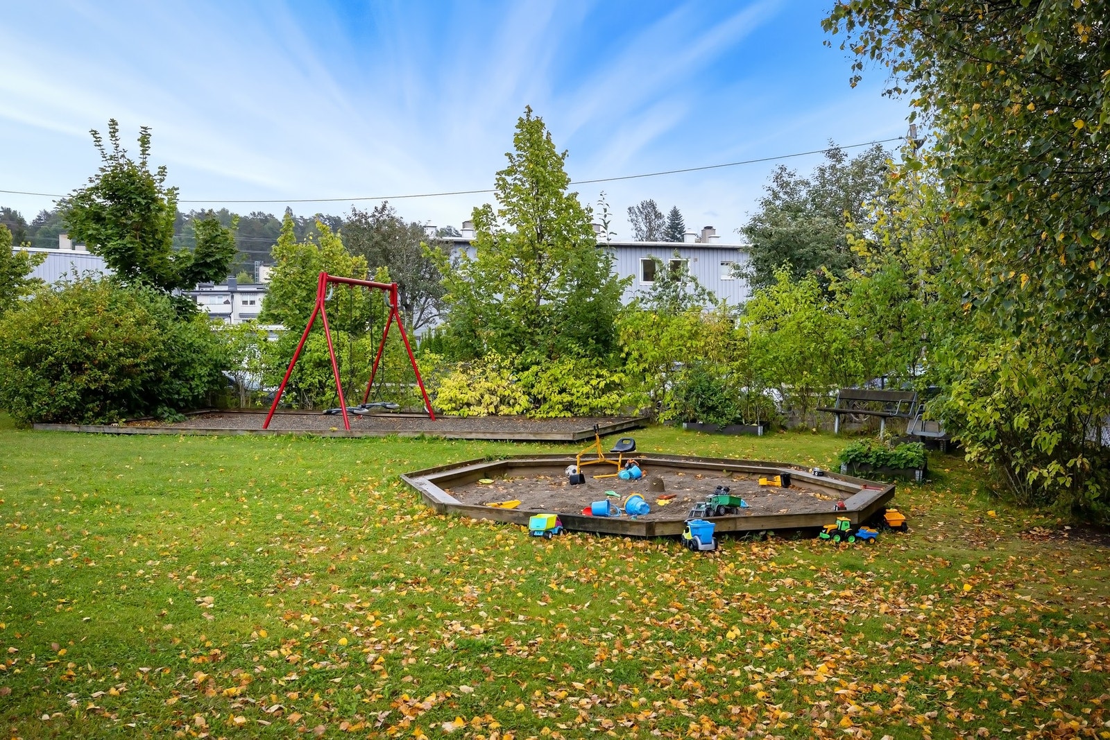 Pent opparbeidet uteområde med sandkasse, huske og beplantning Galleribilde