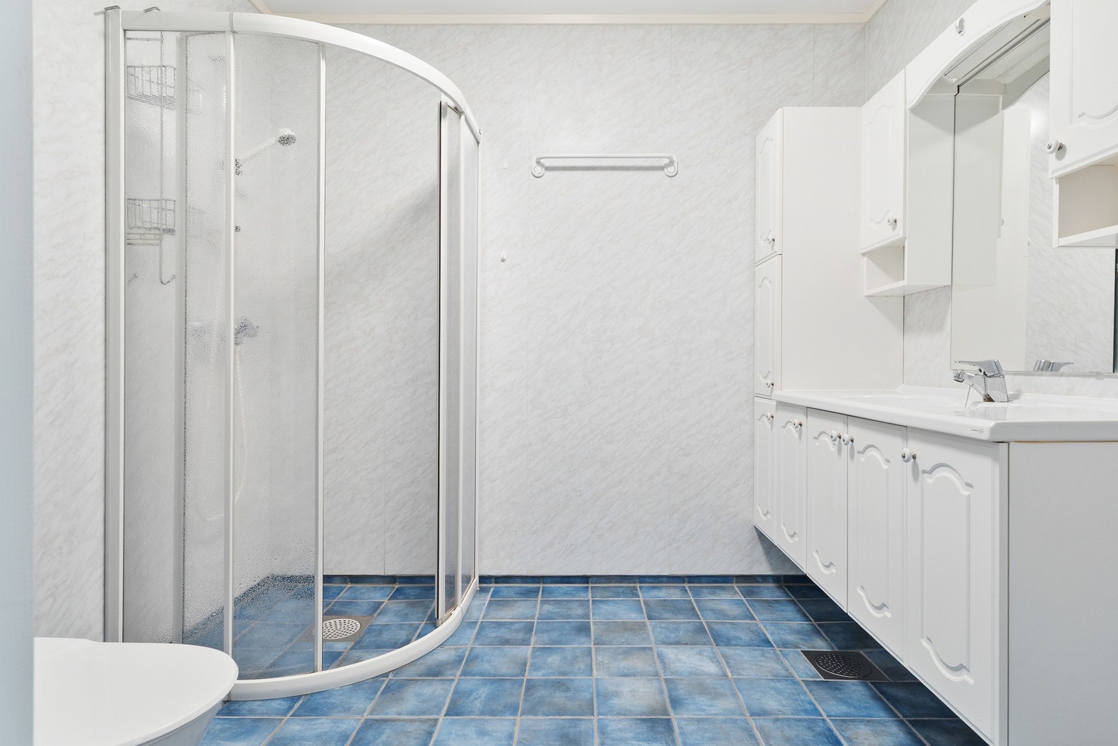 Badet har dusj, toalett og vegghengt innredning med tilhørende speil og det er varme i gulv Galleribilde