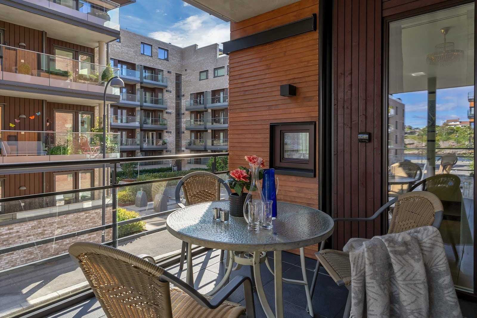 Balkongen er utstyrt med stilrent glassrekkverk som gir uhindret utsikt mot velstelte fellesarealer, Otra og havna. Galleribilde