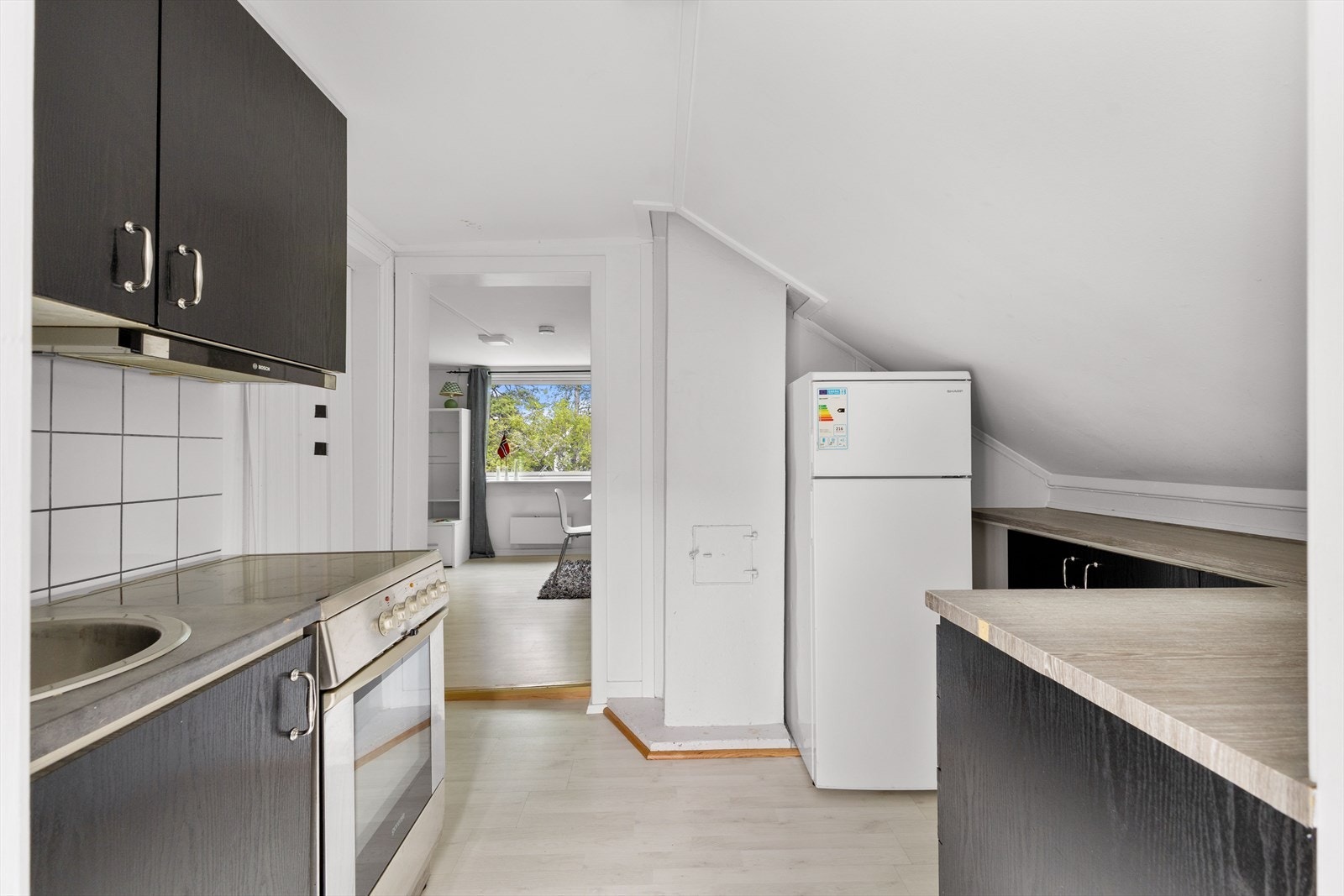 Kjøkkeninnredning med slette fronter og benkeplate i laminat. Praktisk, nedfelt oppvaskkum gir et stilrent og funksjonelt uttrykk Galleribilde