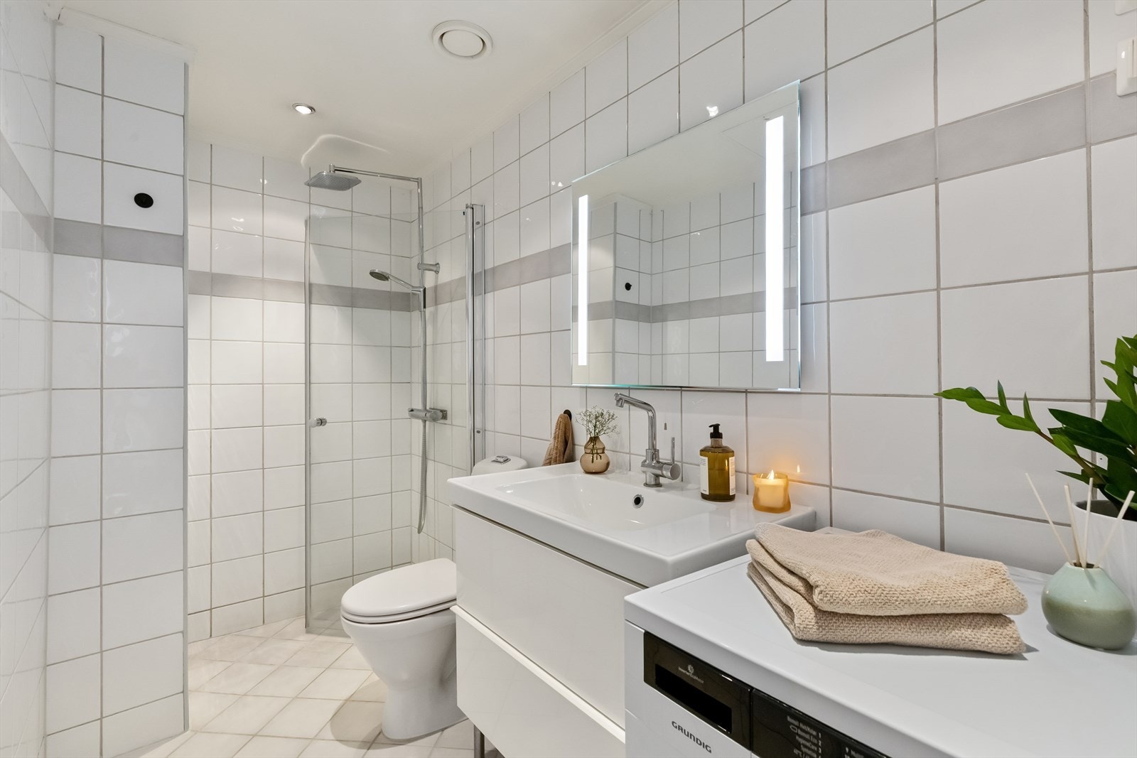 Pent bad med regnfalldusj, opplegg for vaskemaskin, varmekabler i gulv og downlights i himling. Galleribilde