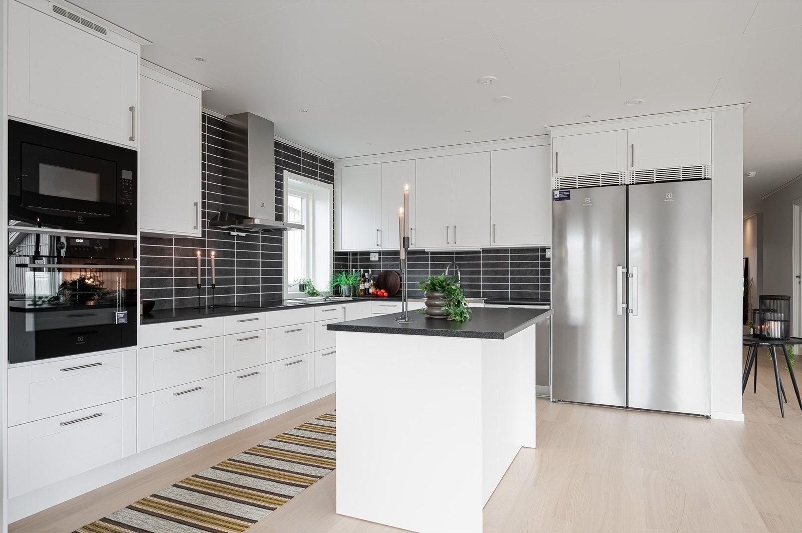 Lekkert og stilrent kjøkken med integrerte hvitevarer og side-by-side kjøleskap/frys. Galleribilde