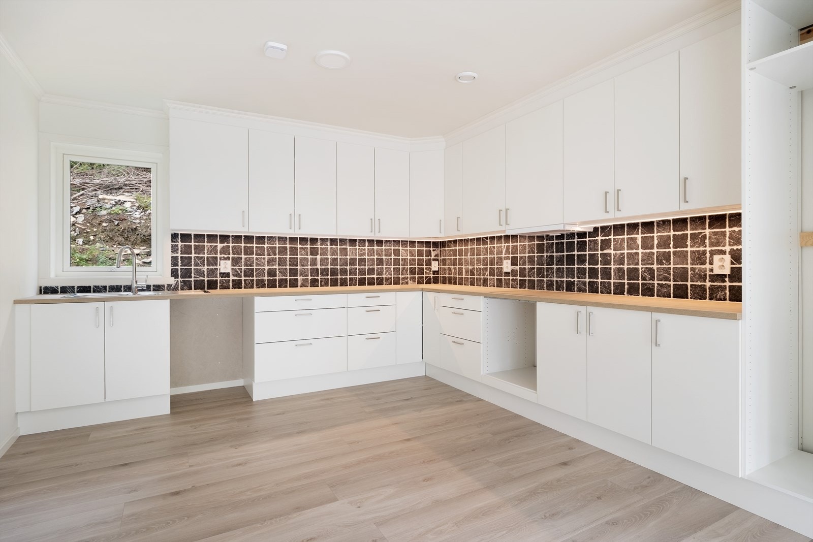 Kjøkkendelen er levert av Sognatre AS og har kvite glatte frontar. På vegg mellom overksåp og benkeflate er det marmorflisar som veggbeskyttelse. Galleribilde