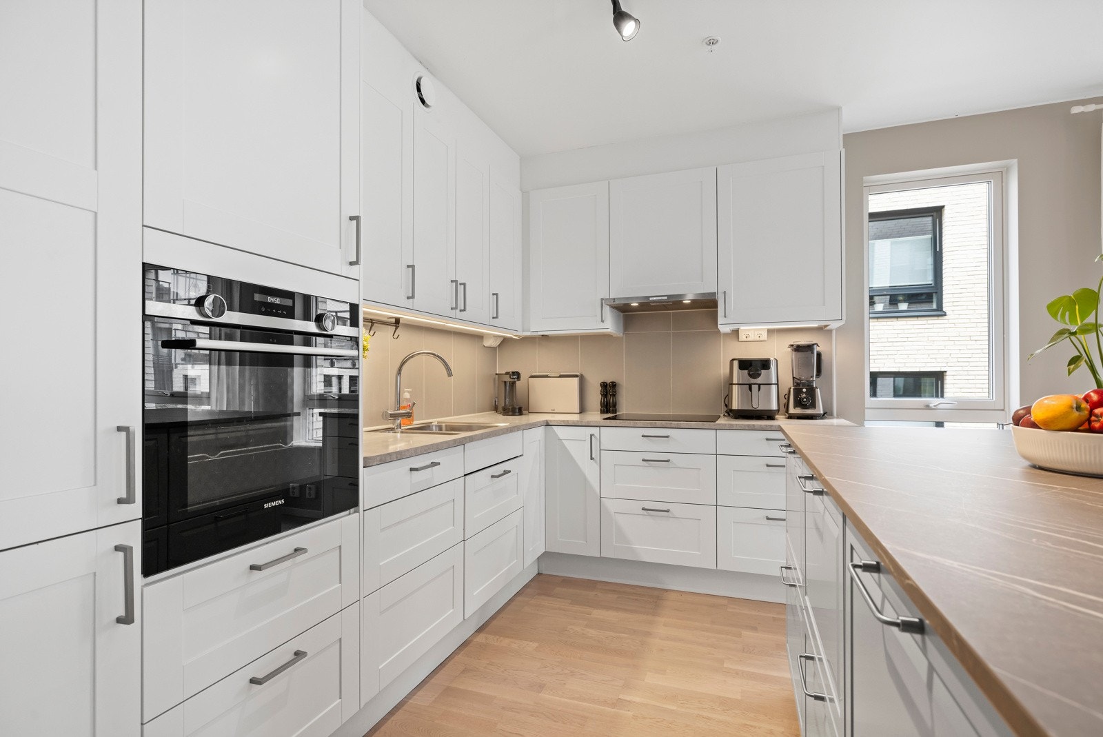 Marbodal kjøkkeninnredning med kjøkkenøy, malte fronter, laminat benkeplater og underlimt oppvaskkum. Galleribilde