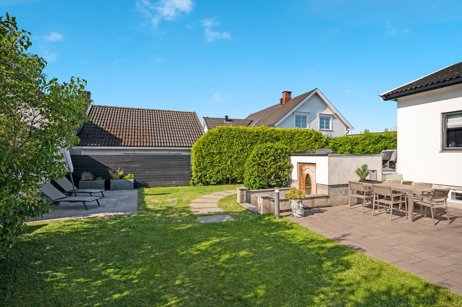 Boligen har en pent opparbeidet hage med flere koselige sitteplasser Galleribilde