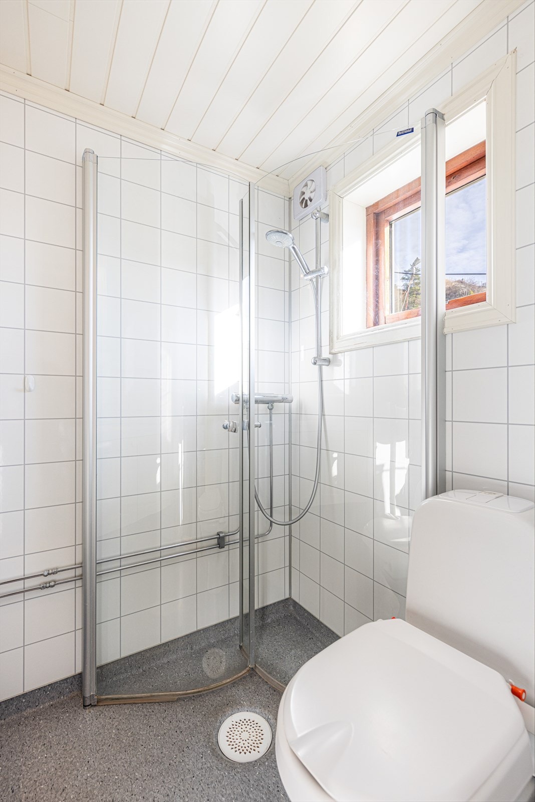 Videre har badet elektriske varmekabler i gulv, gulvmontert toalett og dusjnisje med buede glassdører som kan felles inn når dusjen ikke er i bruk. Galleribilde