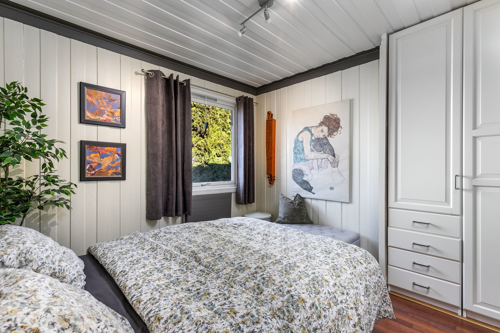 Soverom 1 fremstår som innbydende med lyse veggflater, laminatgulv og et stort vindu som slipper inn godt med lys. Galleribilde