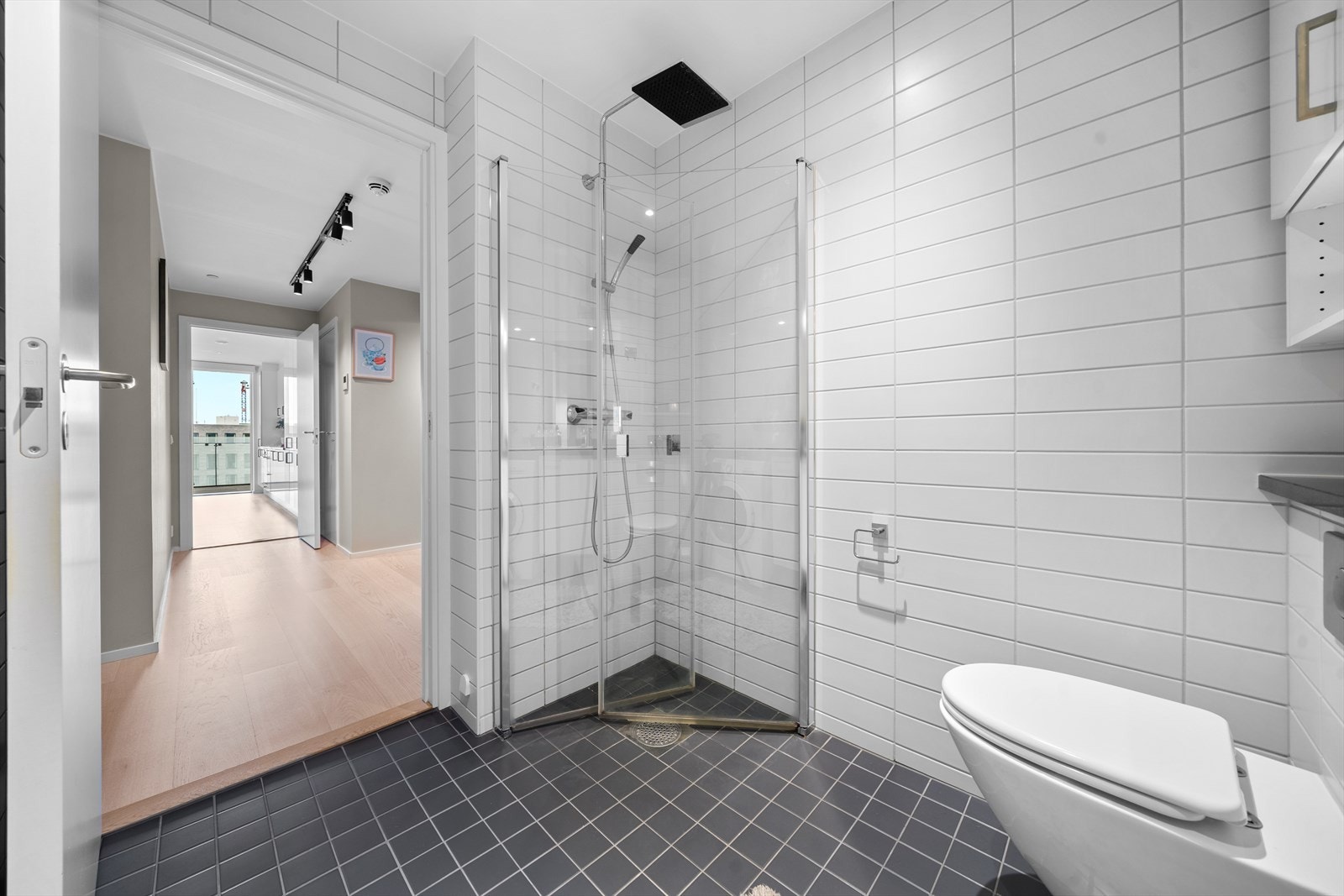 Rommet er helfliset og har varmekabler i gulvet for ekstra komfort. Badet er utstyrt med heldekkende servant på underskap, speil med belysning, vegghengt toalett og dusjhjørne med herdede glassvegger. Galleribilde