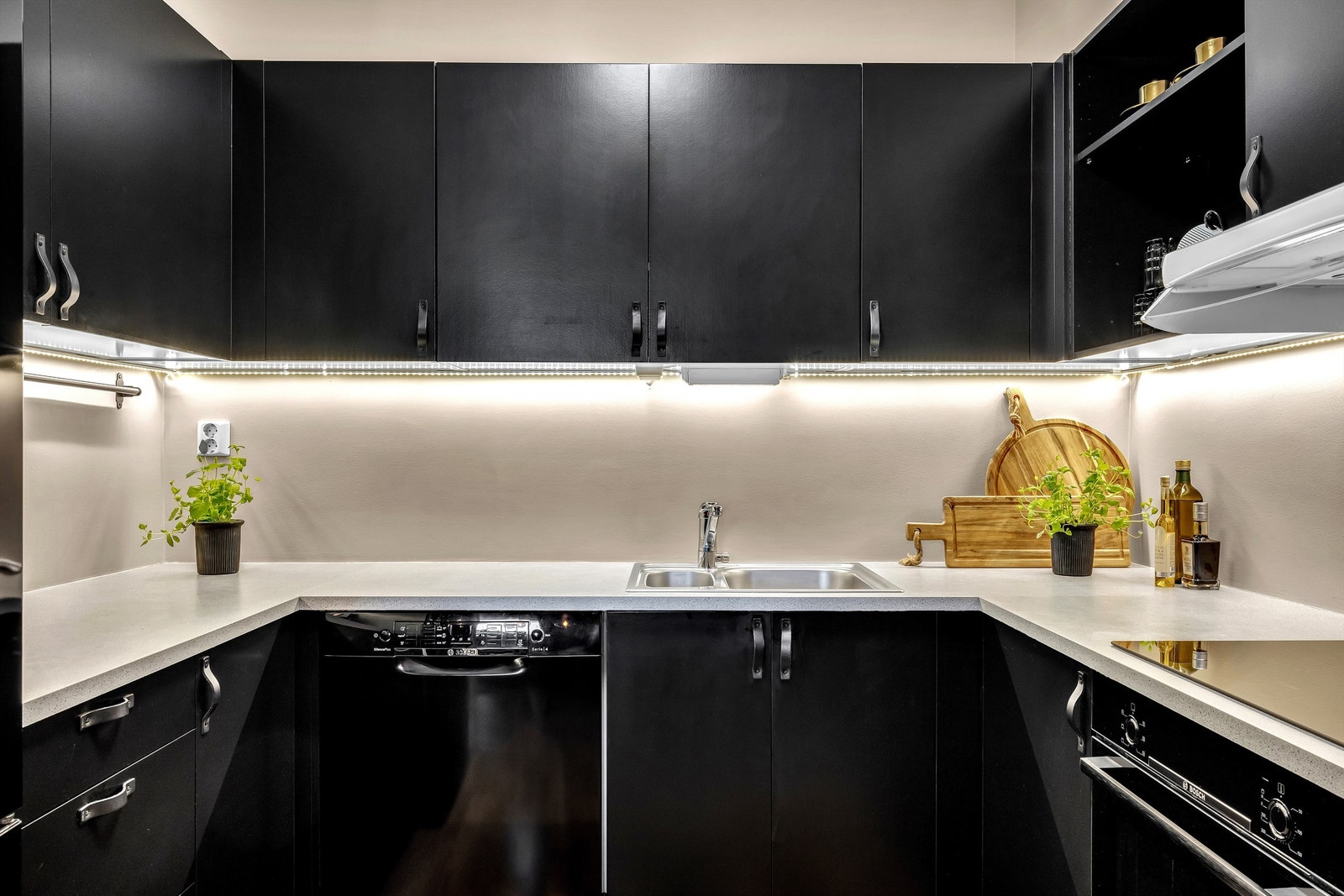 Kjøkken med integrerte hvitevarer som stekeovn og platetopp Galleribilde