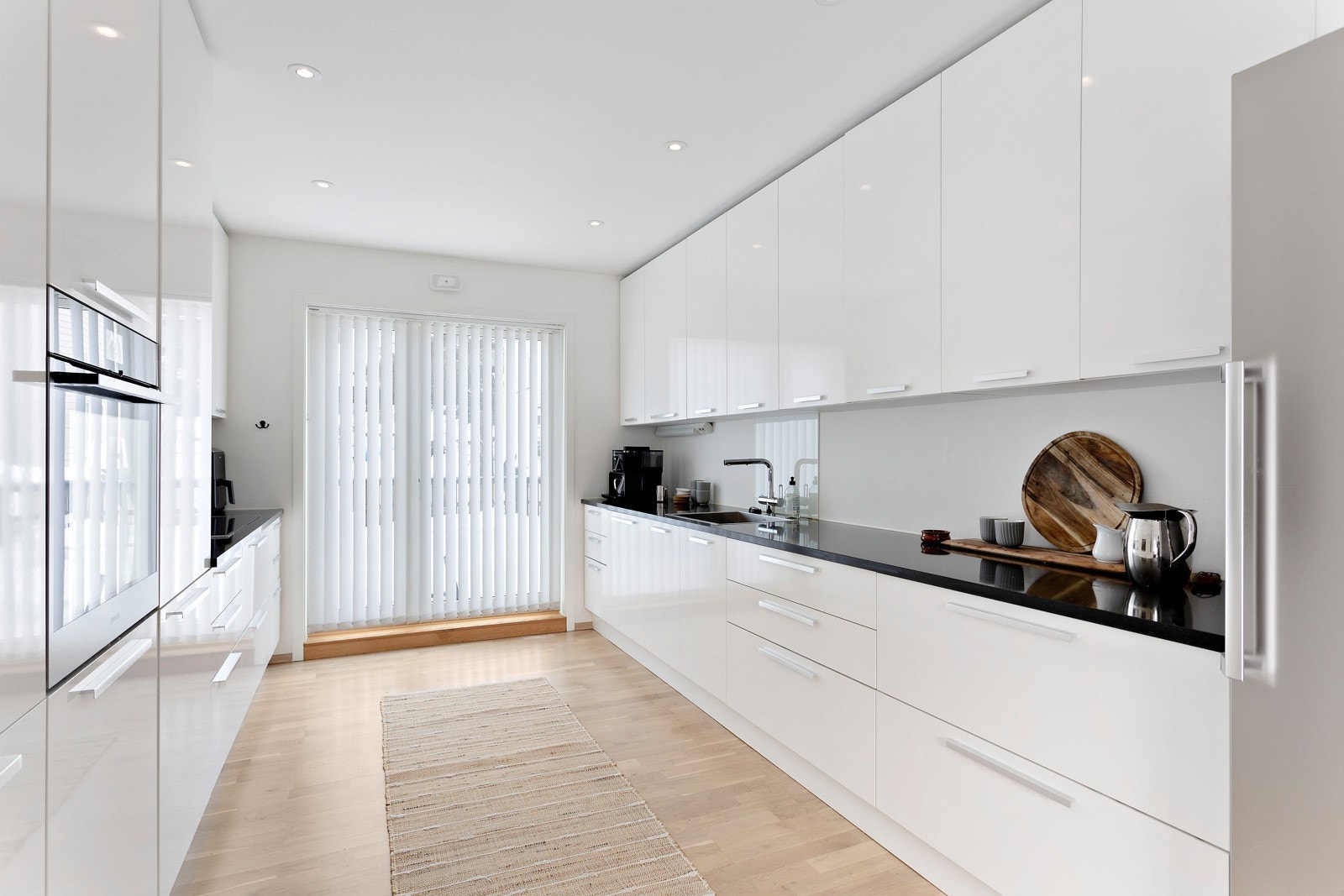 Kjøkkenet har tidløs innredning med slette fronter, kompositt benkeplate og glassplate over oppvakkum og platetopp. Galleribilde