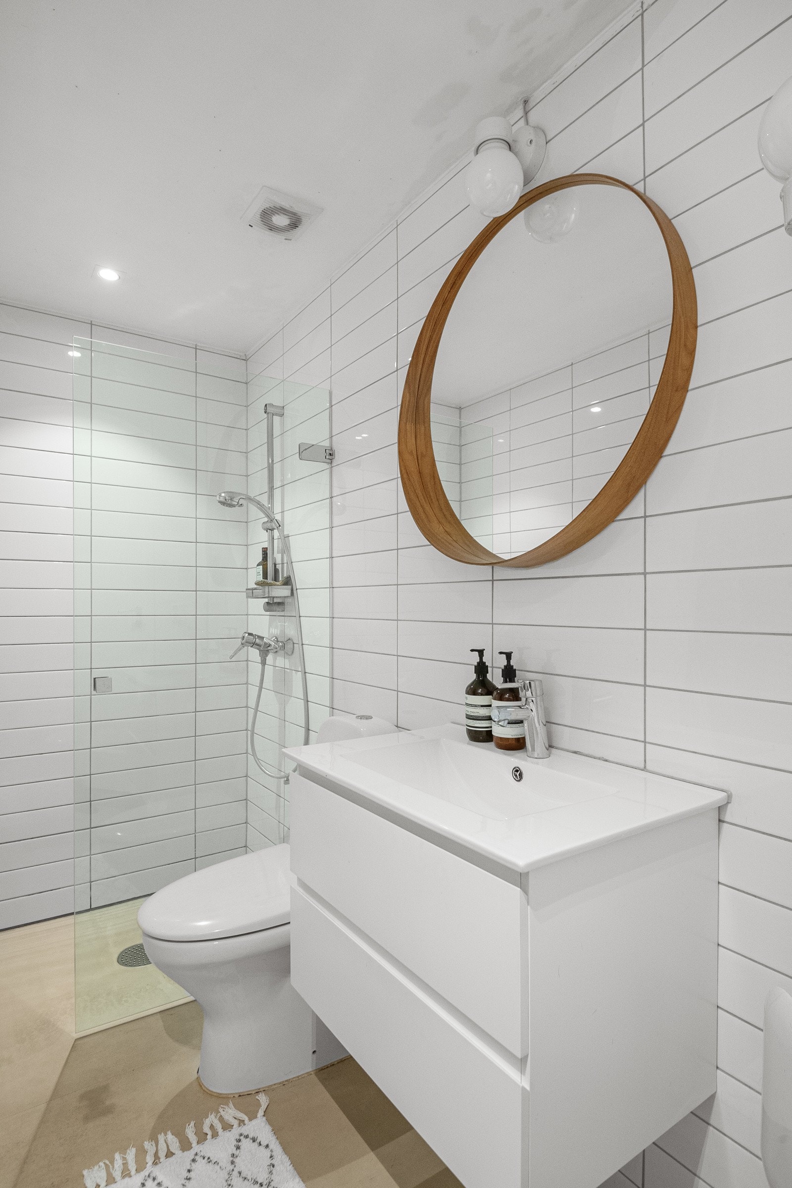 Badet fremstår som lyst og tidsriktig med hvit flis på vegg og mikrosement på gulv. Galleribilde