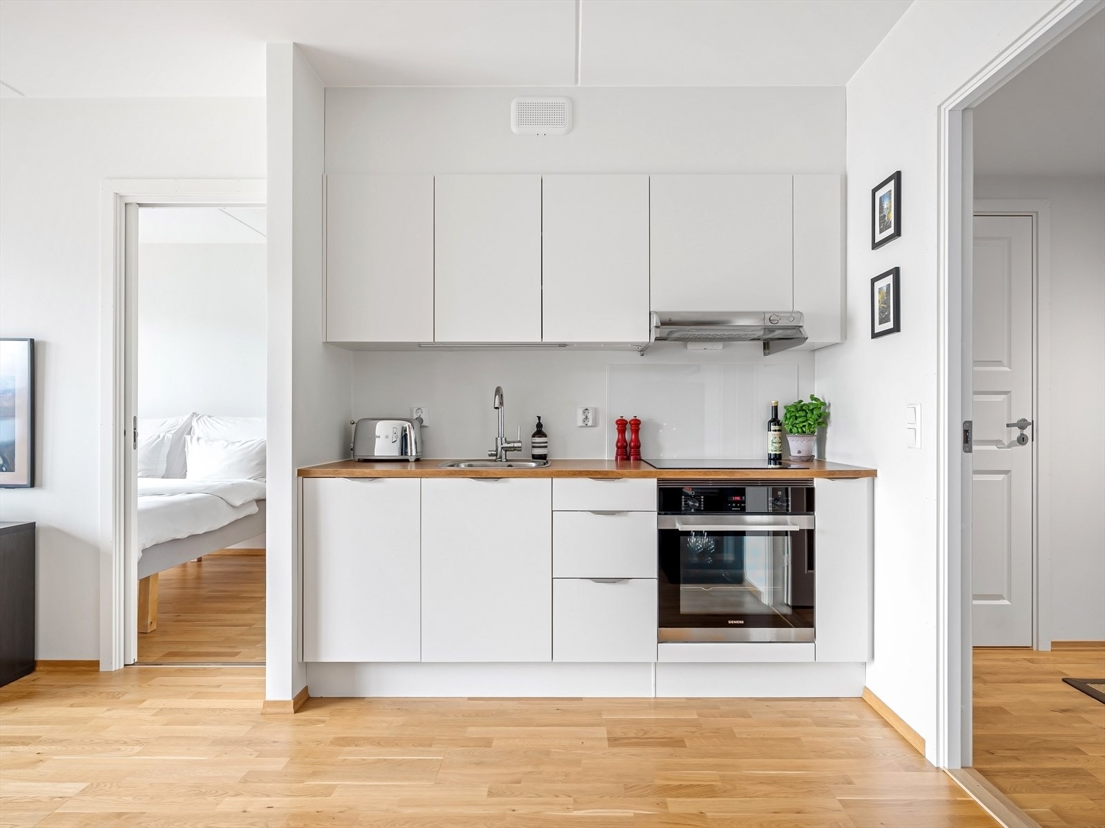 Kjøkken med slette fronter, belysning under overskap og integrerte hvitevarer. Galleribilde