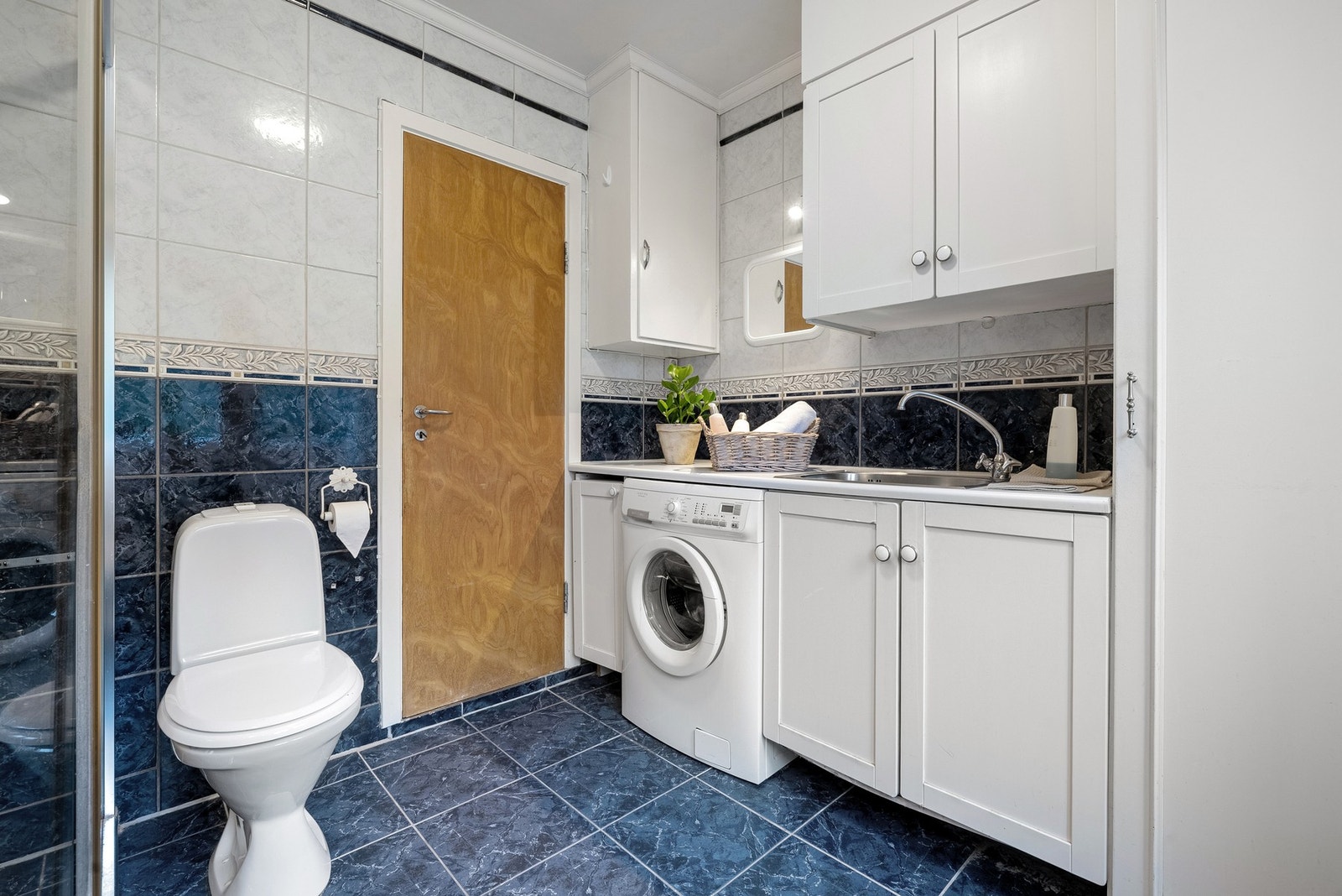 Badet er innredet med baderomsinnredning med nedfelt servant, arbeidsbenk med vask, toalett, dusjvegger/hjørne og opplegg for vaskemaskin. Galleribilde