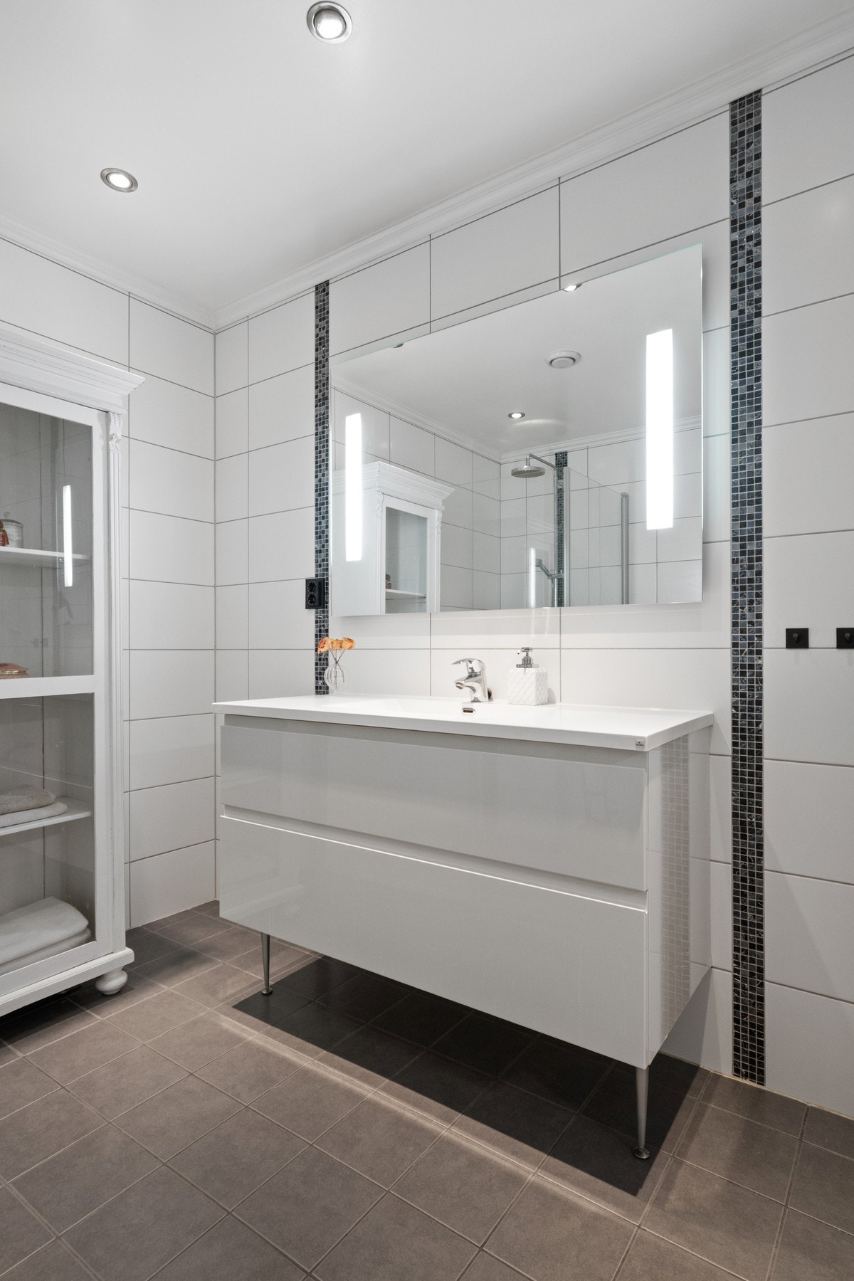 Badet oppe er romslig, innredet med hvite veggfliser og lysegrå gulvfliser. Galleribilde