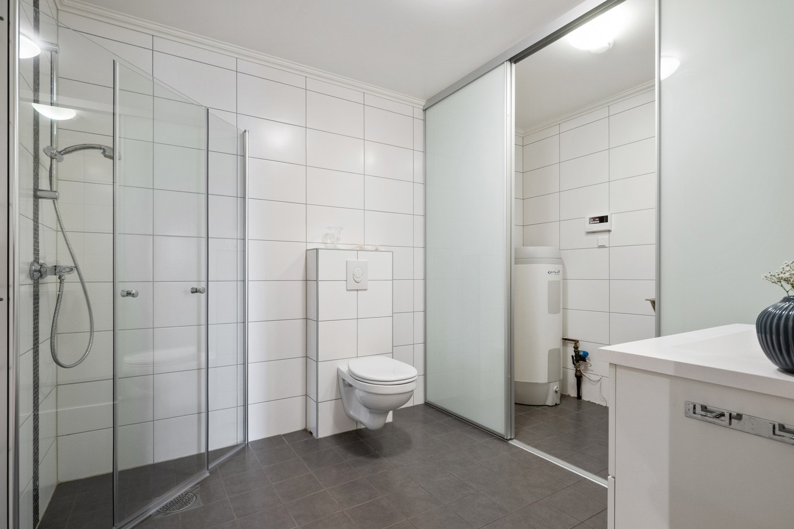 Skjult bak store skyvedører har badet et eget vaskerom med bereder, utslagsvask og opplegg for vaskemaskin. Galleribilde