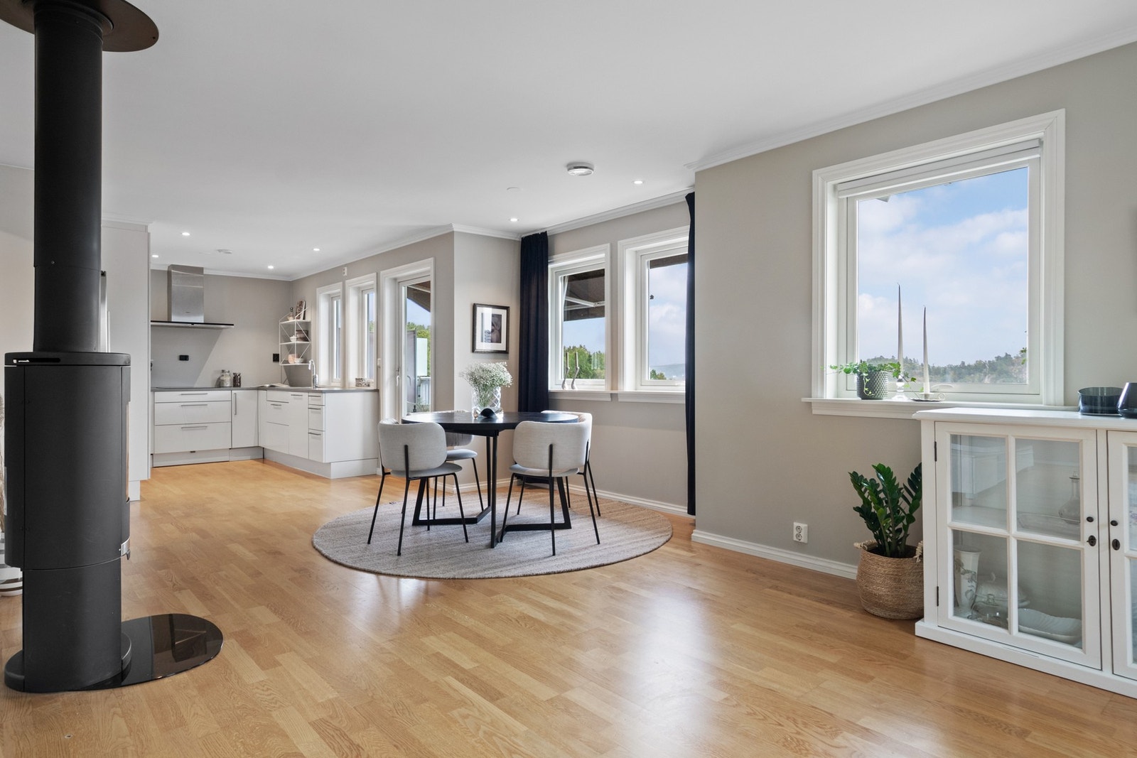 Kjøkkenet er oppført i en smart u-form, med hvite, glatte fronter, dobbel oppvaskkum og lysegrå benkeplate av laminat. Galleribilde