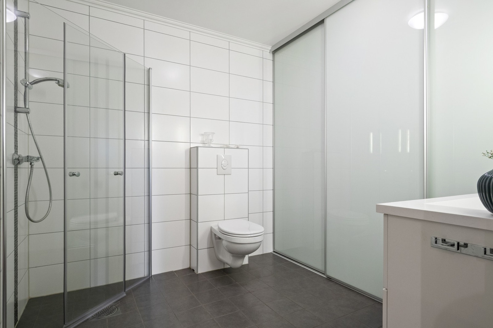 Badet nede har grå gulvfliser og hvite veggfliser for et delikat uttrykk. Galleribilde