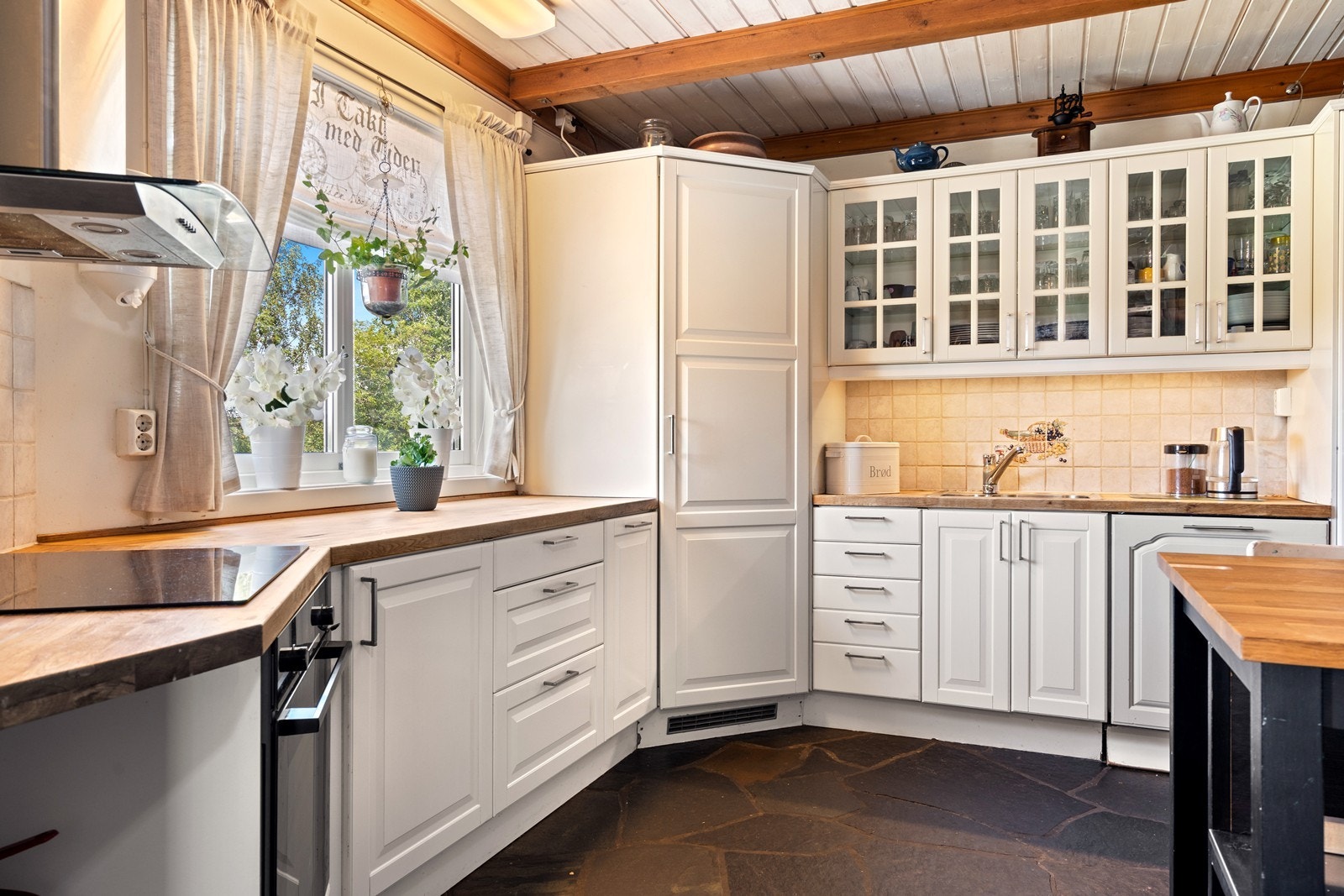 Lyst og romslig kjøkken med lyse, profilerte fronter og benkeplater i eik. Galleribilde