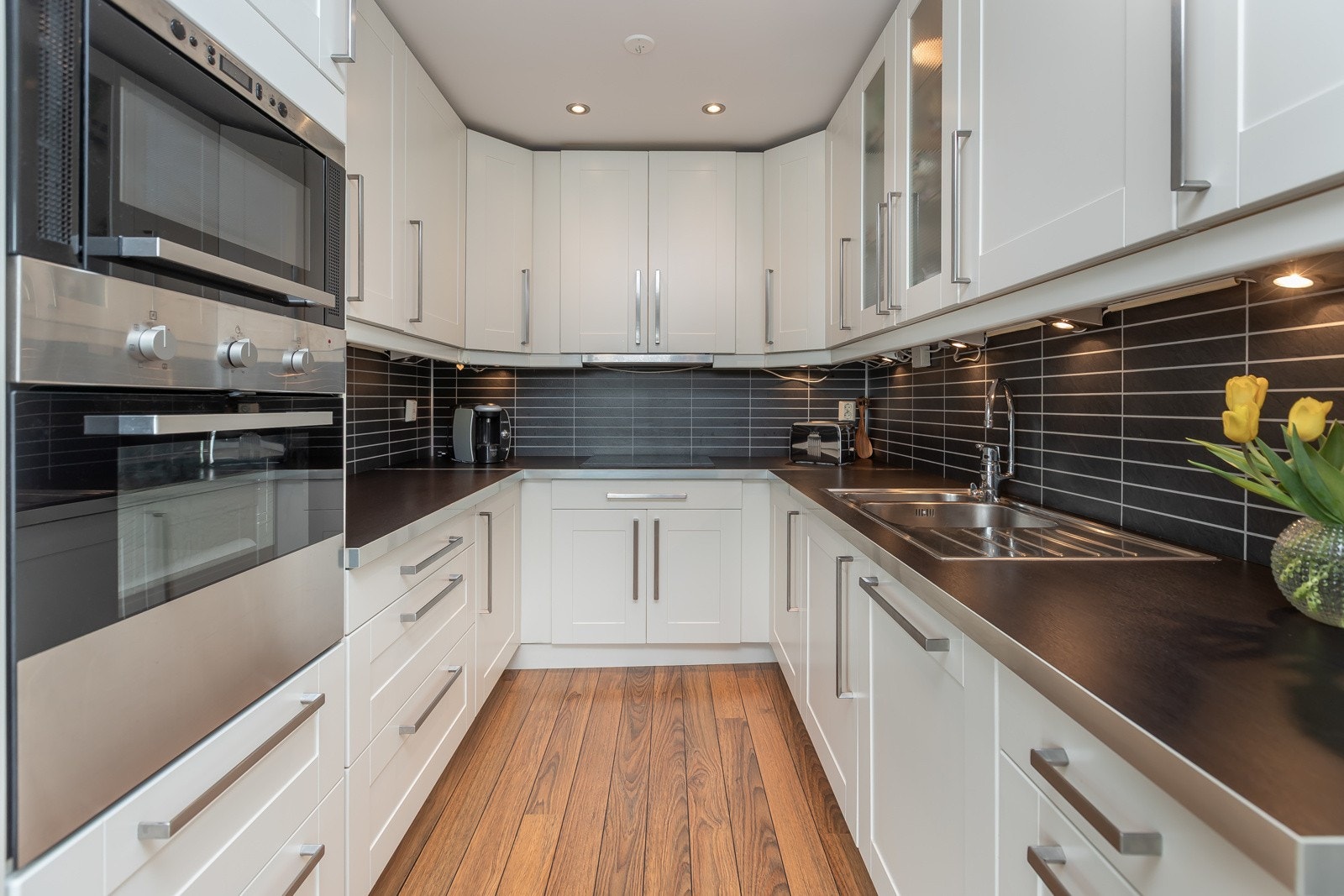 Stilig kjøkken med god oppbevaringsplass og takhøye skap. Galleribilde