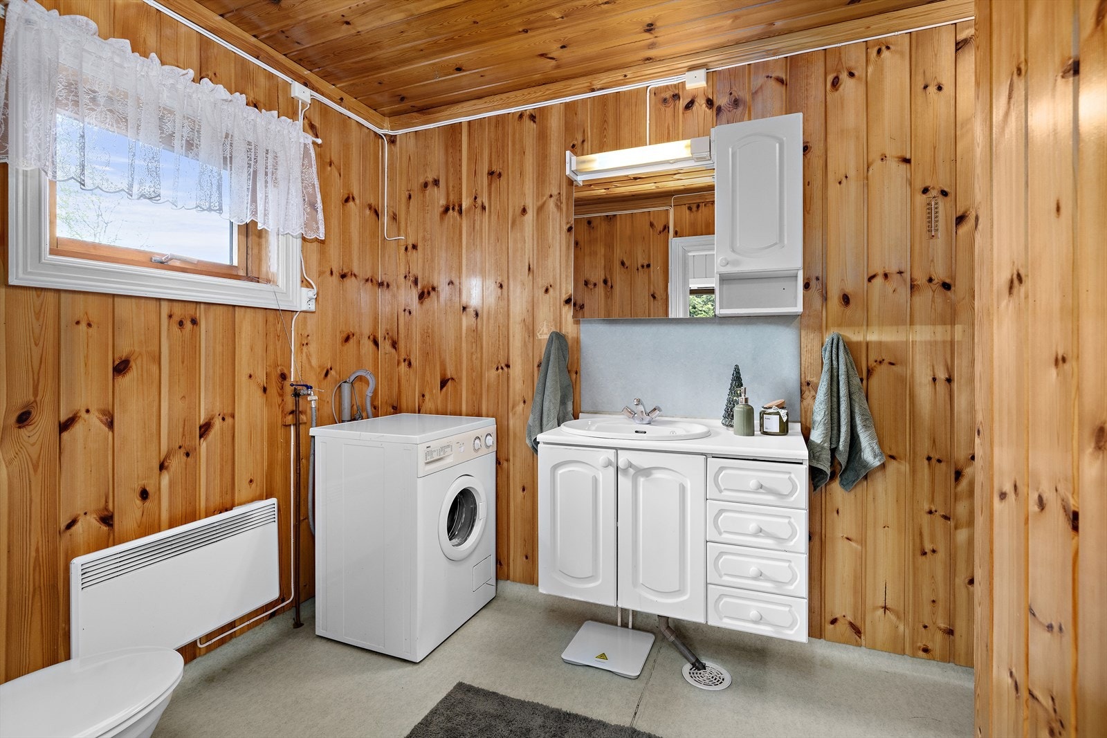 Badet er utstyrt med servantinnredning med nedfelt servant, toalett, dusjhjørne med dusjvegger og opplegg for vaskemaskin. Galleribilde