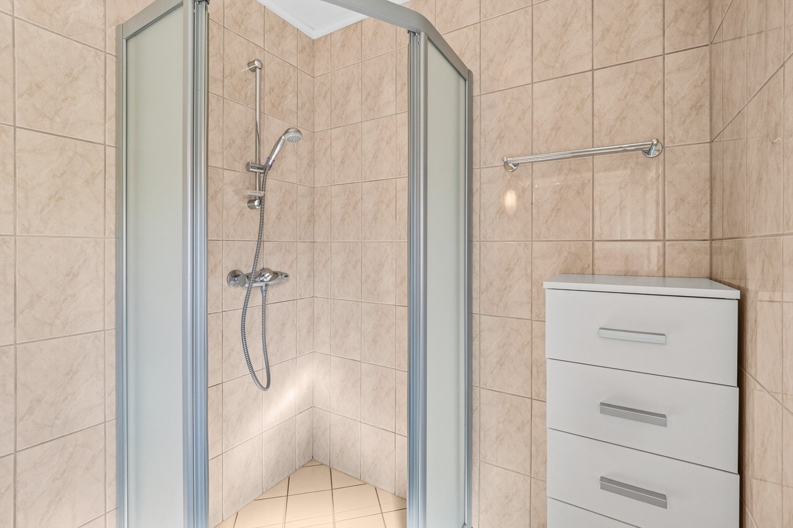 Dusjhjørnet har dusjvegger med skyvedør, og veggmontert dusjsett med hånddusj. Galleribilde