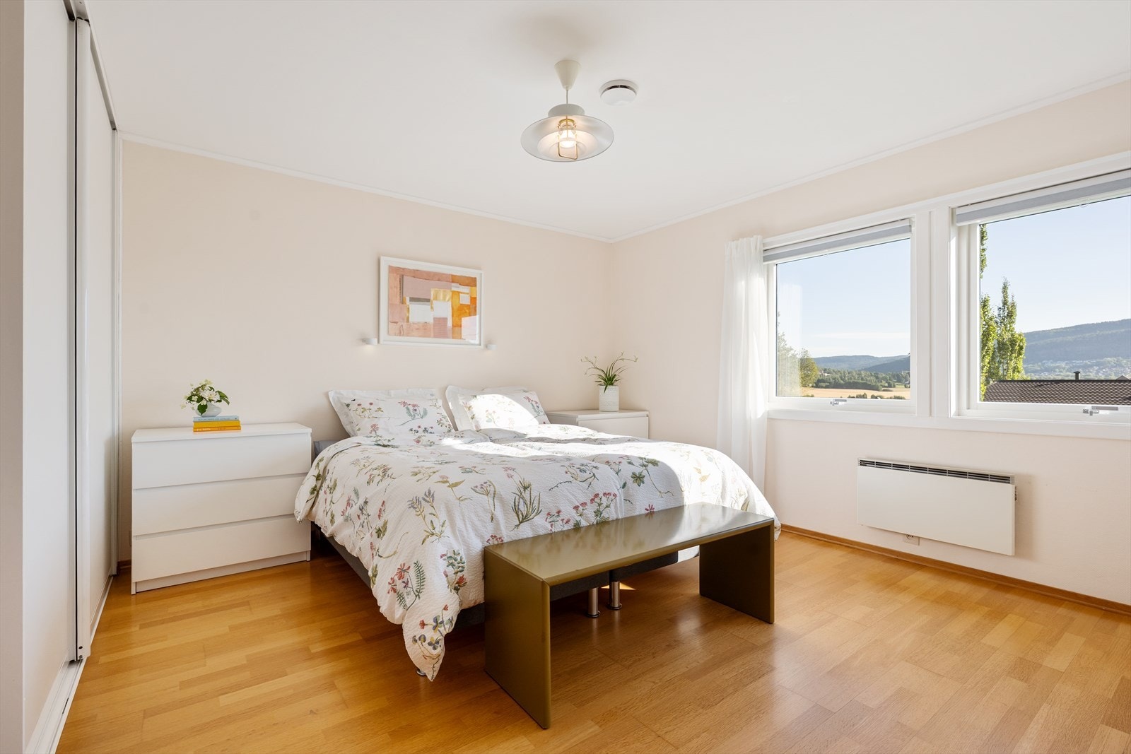 Romslig hovedsoverom med plass til dobbeltseng og tilhørende nattbord samt store vindusflater. Galleribilde