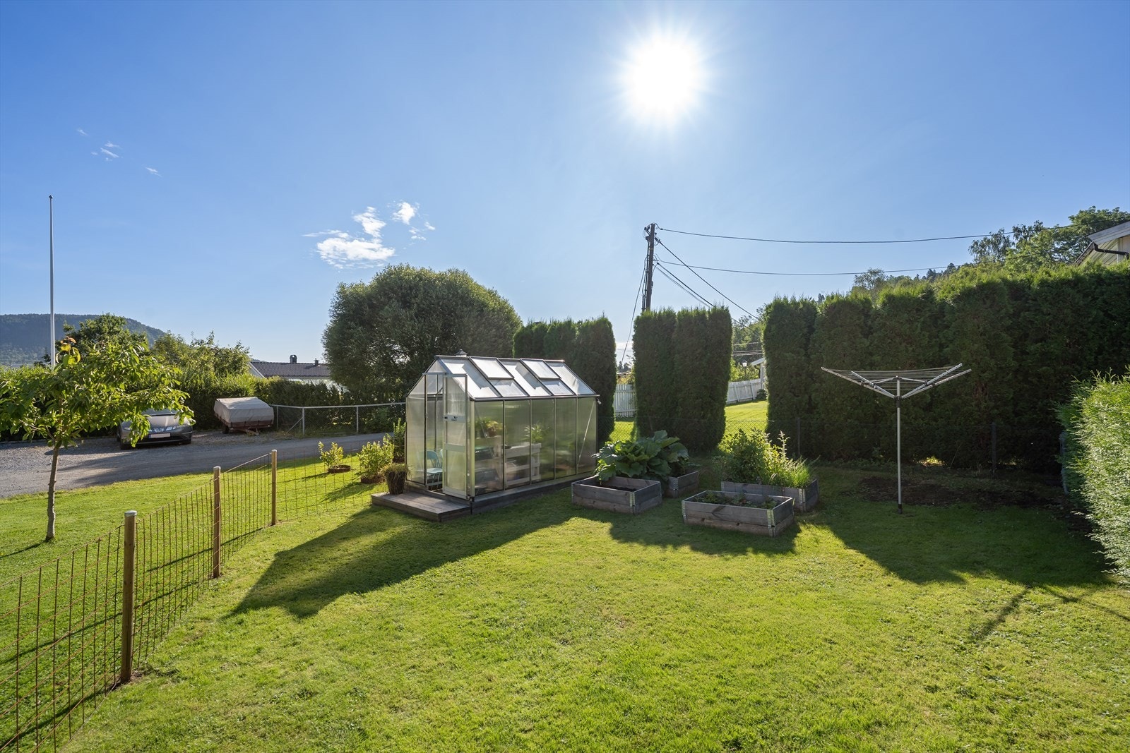 Skjermet hage med frodig beplantning, grønnsaksbed og drivhus og bærbusker. Galleribilde