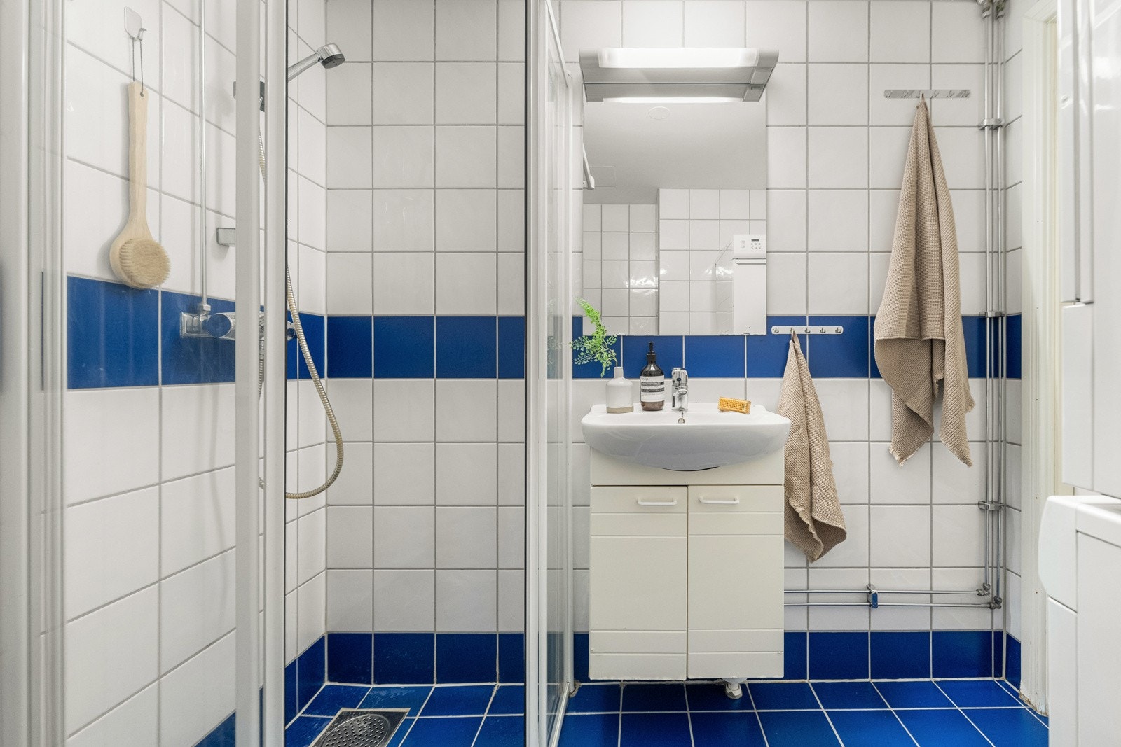 Flislagt bad med dusjhjørne og opplegg for vaskemaskin og tørketrommel Galleribilde