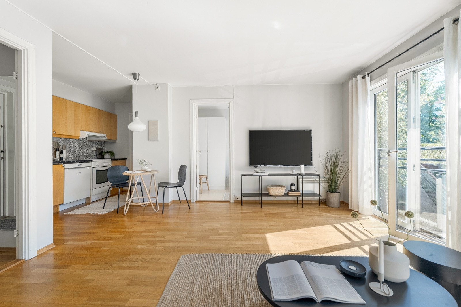 Åpen stue- og kjøkkenløsning med parkett på gulv og lyse overflater Galleribilde