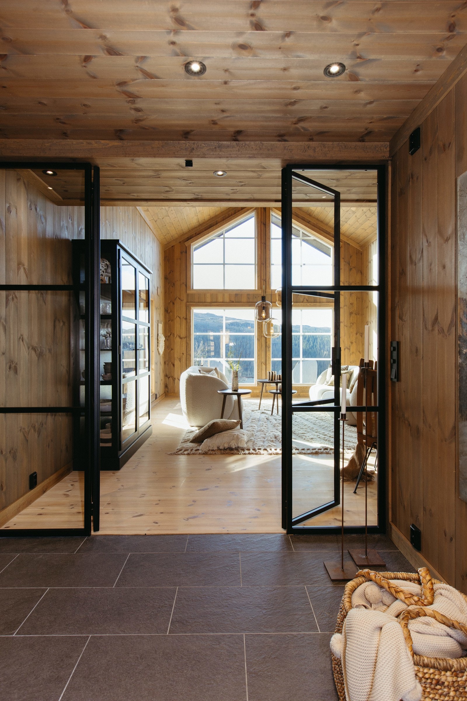 Hall og stue/kjøkken adskilt med glassvegg og dører i smijern fra den lokale produsenten Myhre Smie gir hytten et ekslusivt uttrykk. Galleribilde