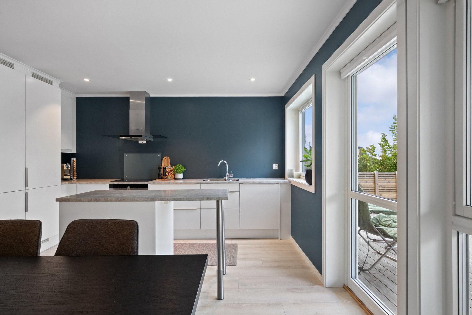 Gulvet har enstavs laminat, og veggene er malt i dyp blåfarge som gir kontrast til kjøkkeninnredningen. Galleribilde