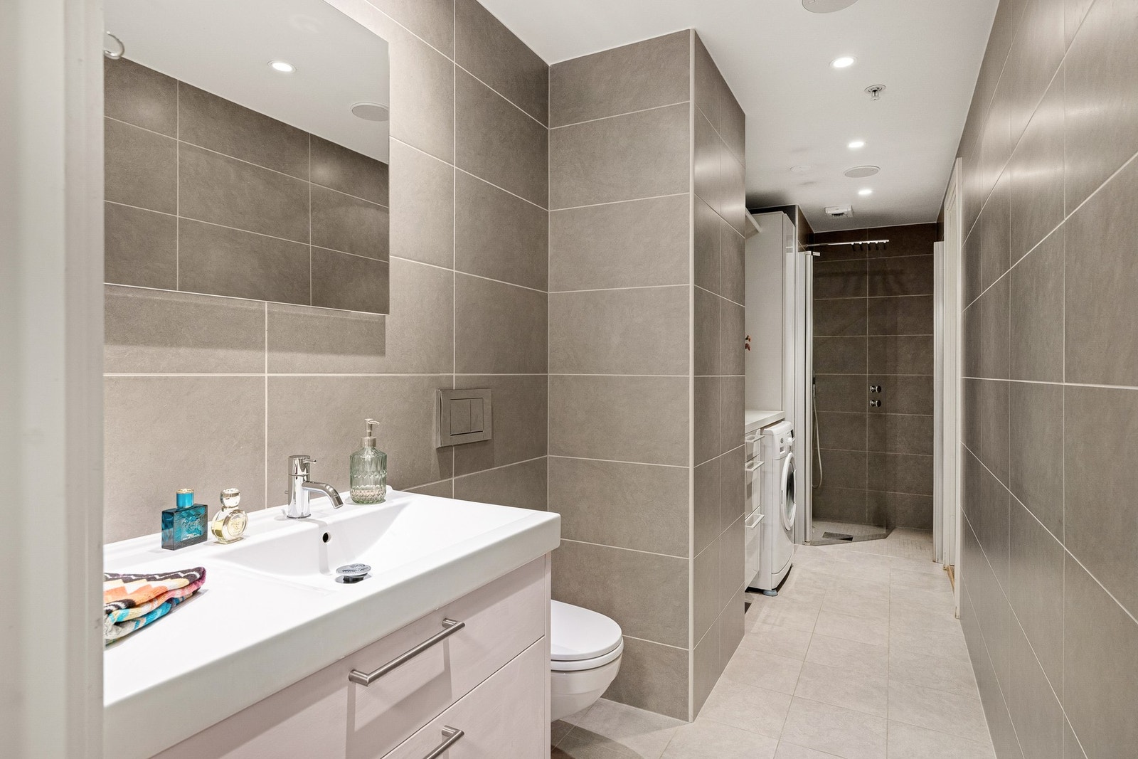 Pent flislagt bad med plasstilpasset nisje for vaskemaskin og oppbevaring. Galleribilde