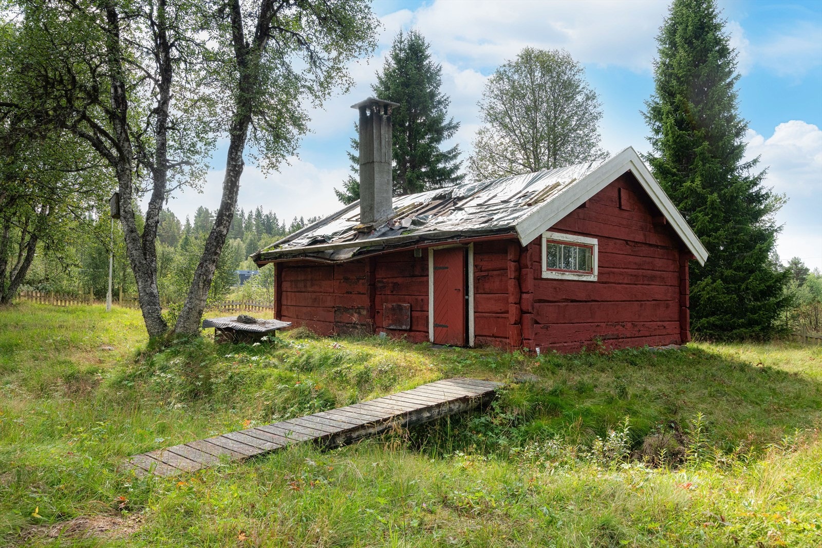 Hytta ligger usjenert og tilbaketrukket til på en solrik, åpen slette omgitt av småskog. Galleribilde