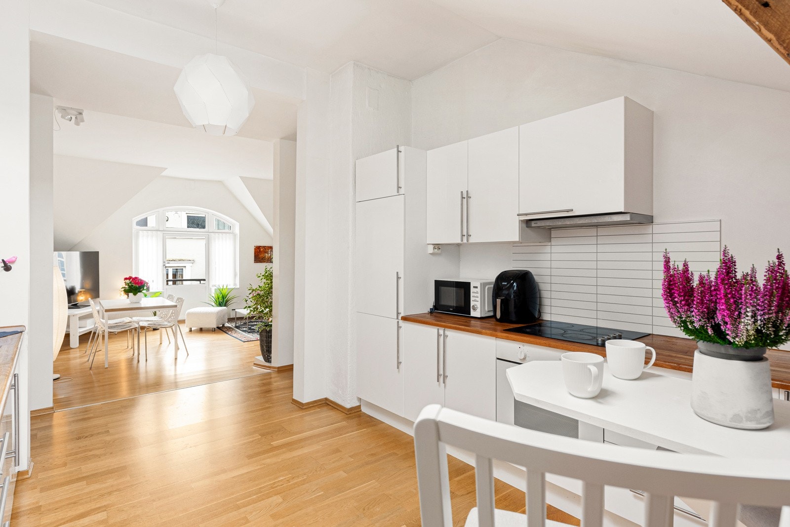 Kjøkkenet har hvit, slett kjøkkeninnredning med benkeplate i eik Galleribilde