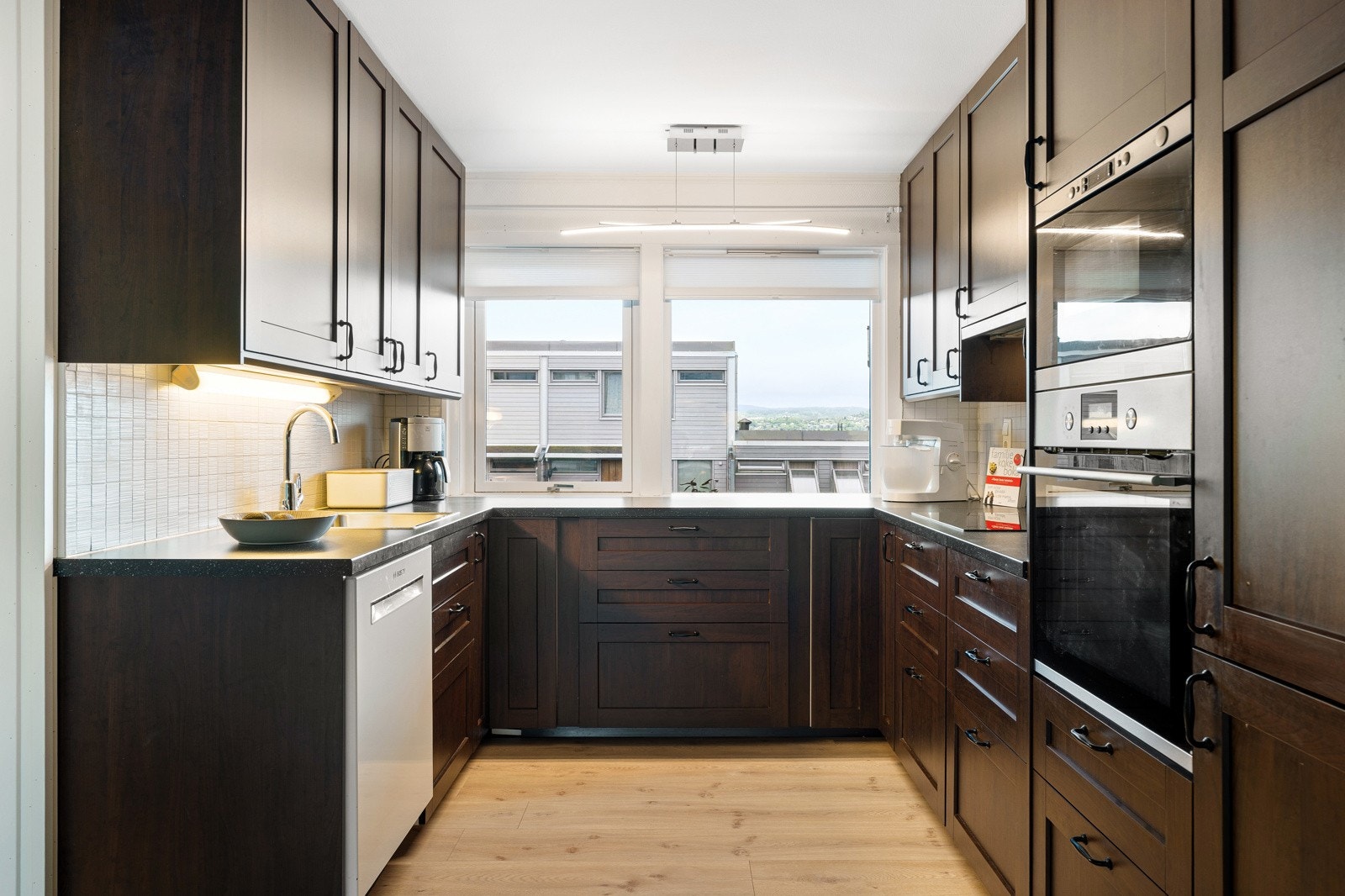 Kjøkkenet fremstår stilrent med en mørk innredning og har rikelig med benk- og skapplass. Galleribilde