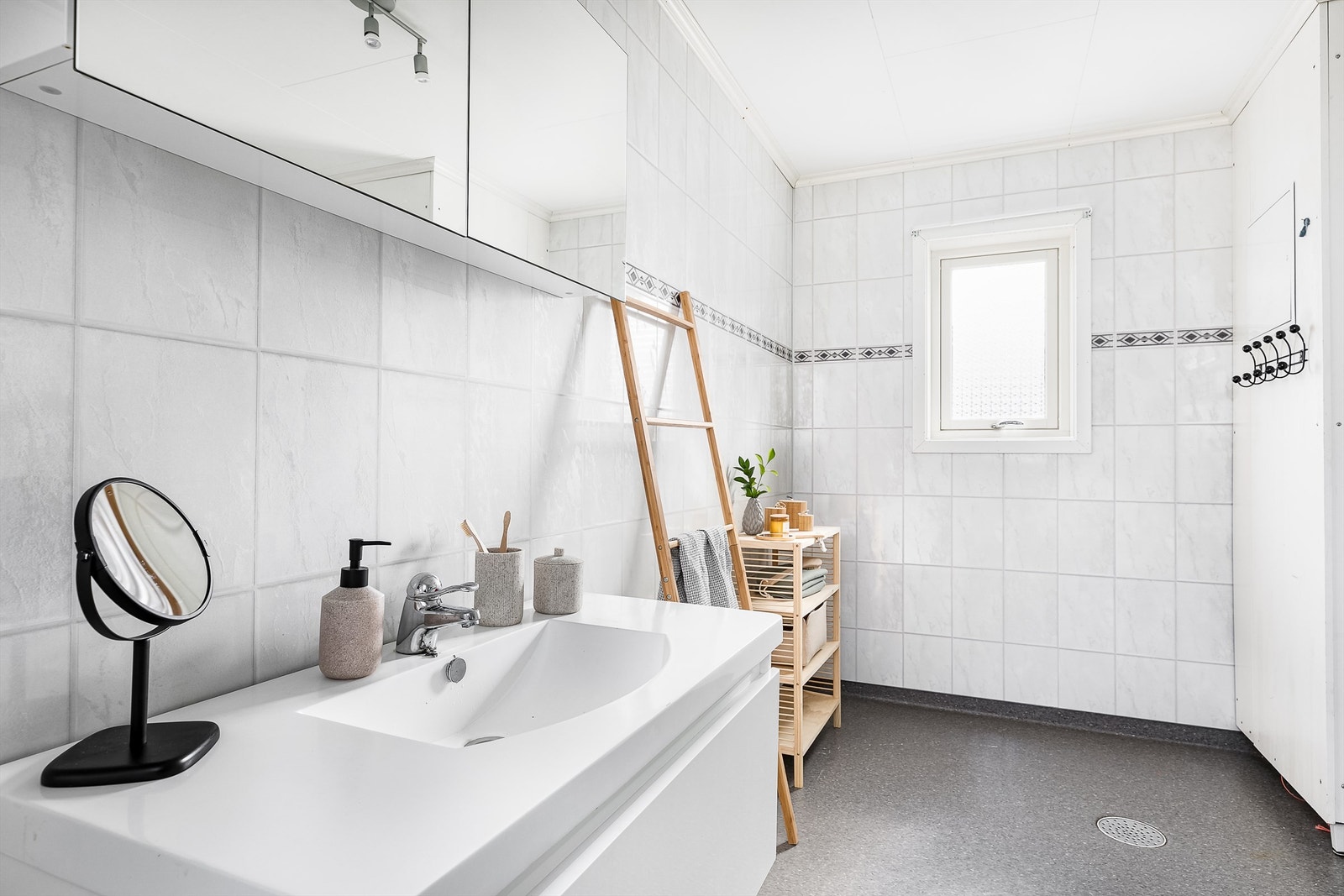 Badets gulv er utført med belegg, veggene med flis-mønstrede våtromsplater. I gulvet er det også elektrisk varme. Galleribilde