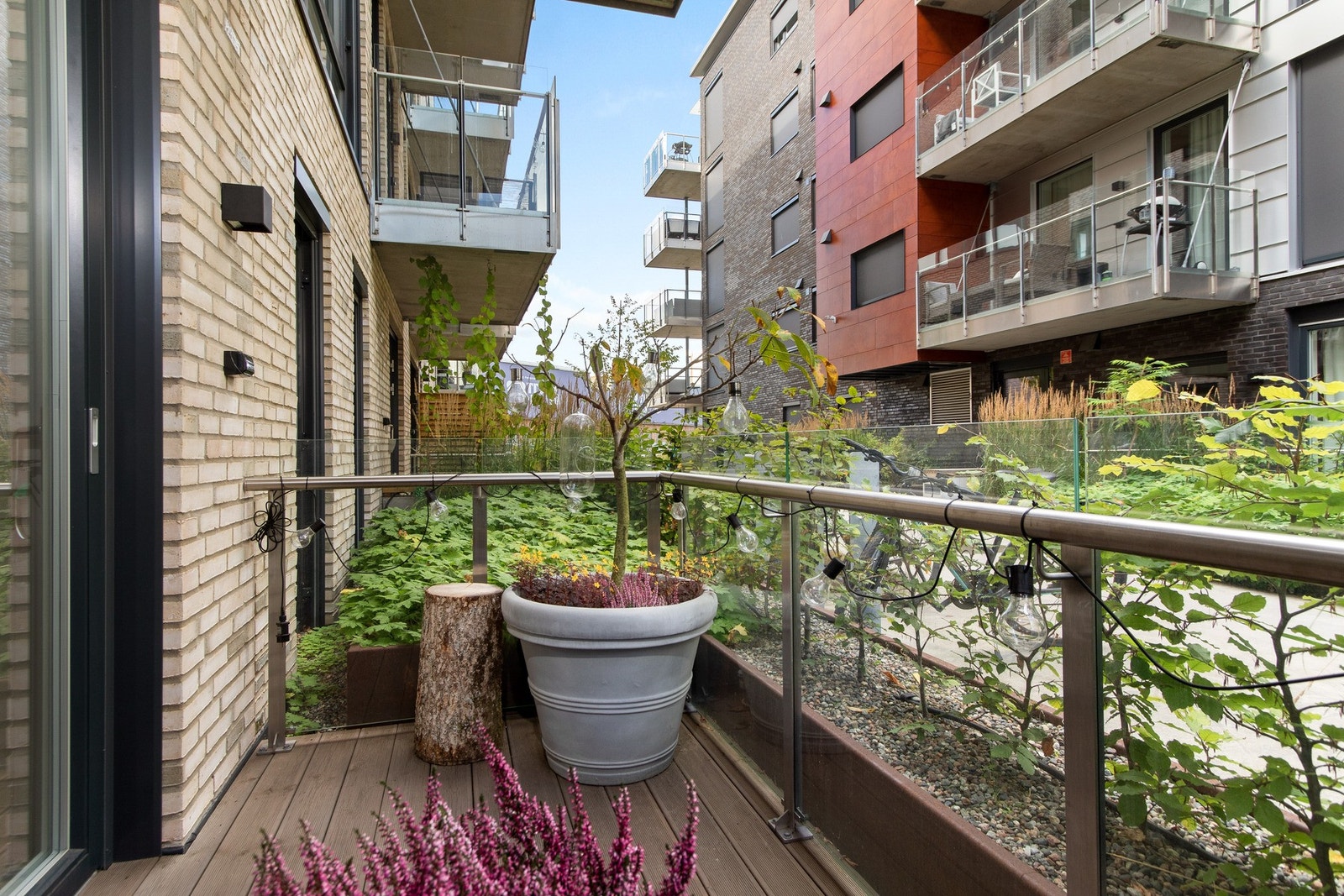 Uteplassen har rekkverk i metall med glass, terrassebord på dekke og strømstikk. Galleribilde