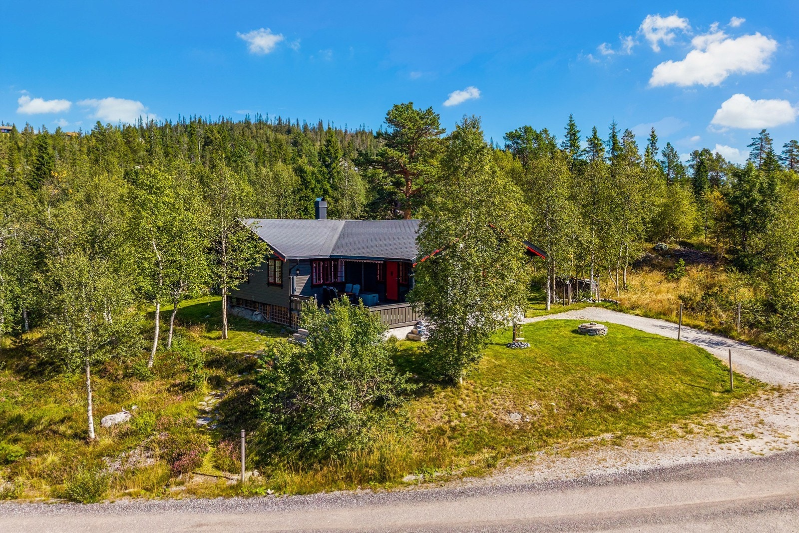 Tomten er opparbeidet med gruslagt innkjørsel på fremsiden av hytta, med plass til parkering for flere biler. Galleribilde