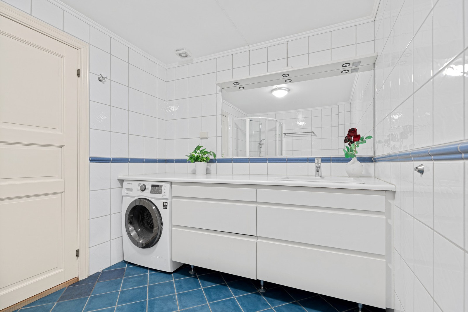 Baderommet er innredet med toalett, dusjkabinett, opplegg for vaskemaskin og servant. Praktisk benkeplate og gode lagringsmuligheter. Galleribilde