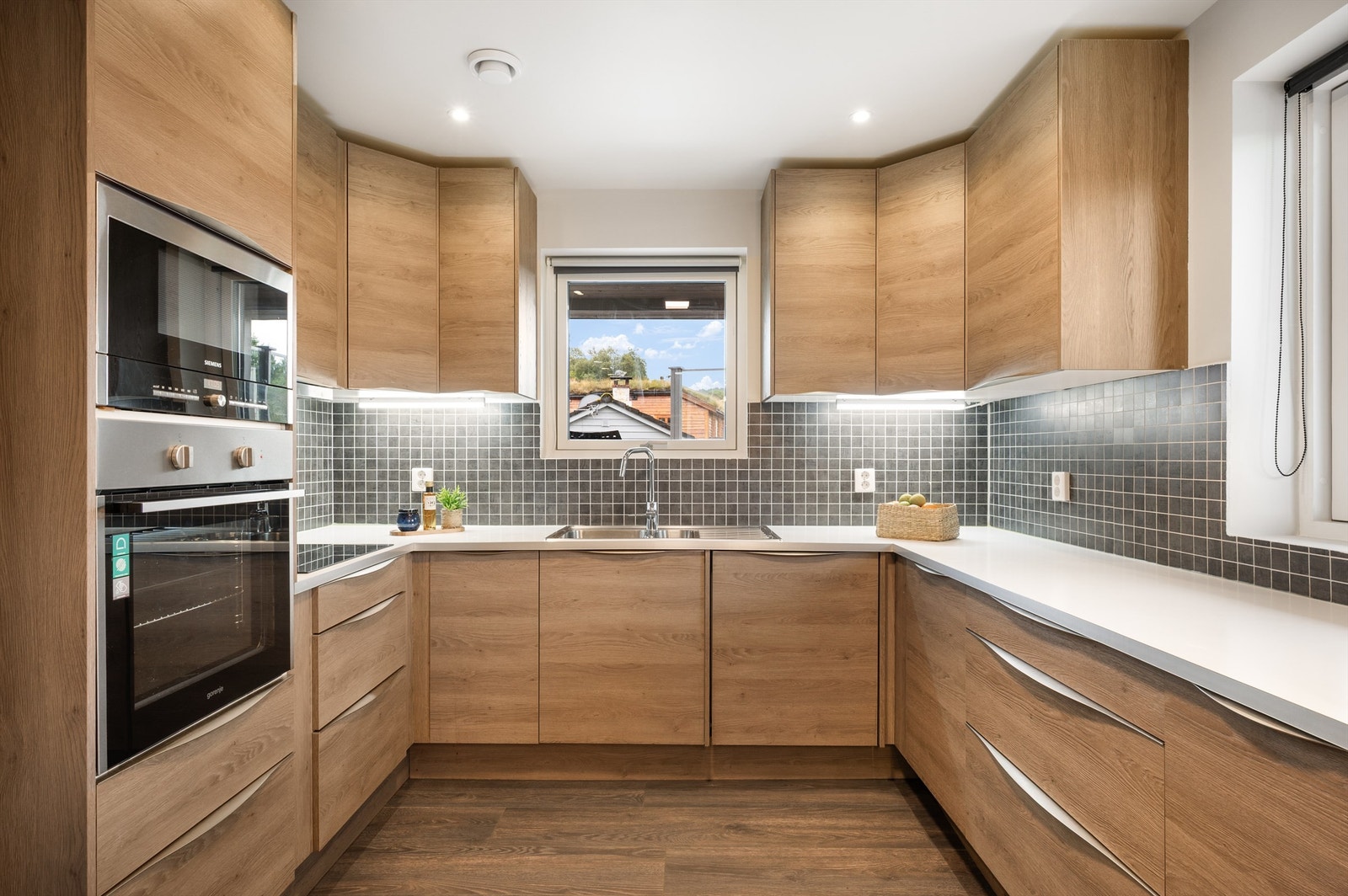 Lekkert kjøkken med integrerte hvitevarer som platetopp, stekeovn, mikro, oppvaskmaskin og kjøleskap m/ frys. Galleribilde