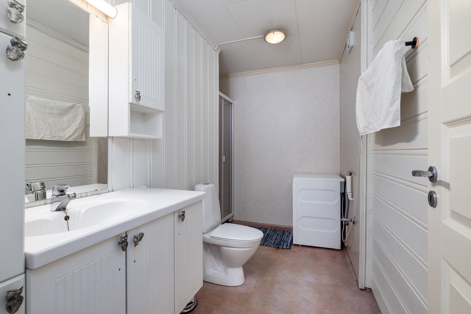 Badet har vegger med panel og våtromstapet, vinylbelegg på gulv og er utstyrt med elektriske varmekabler. Galleribilde