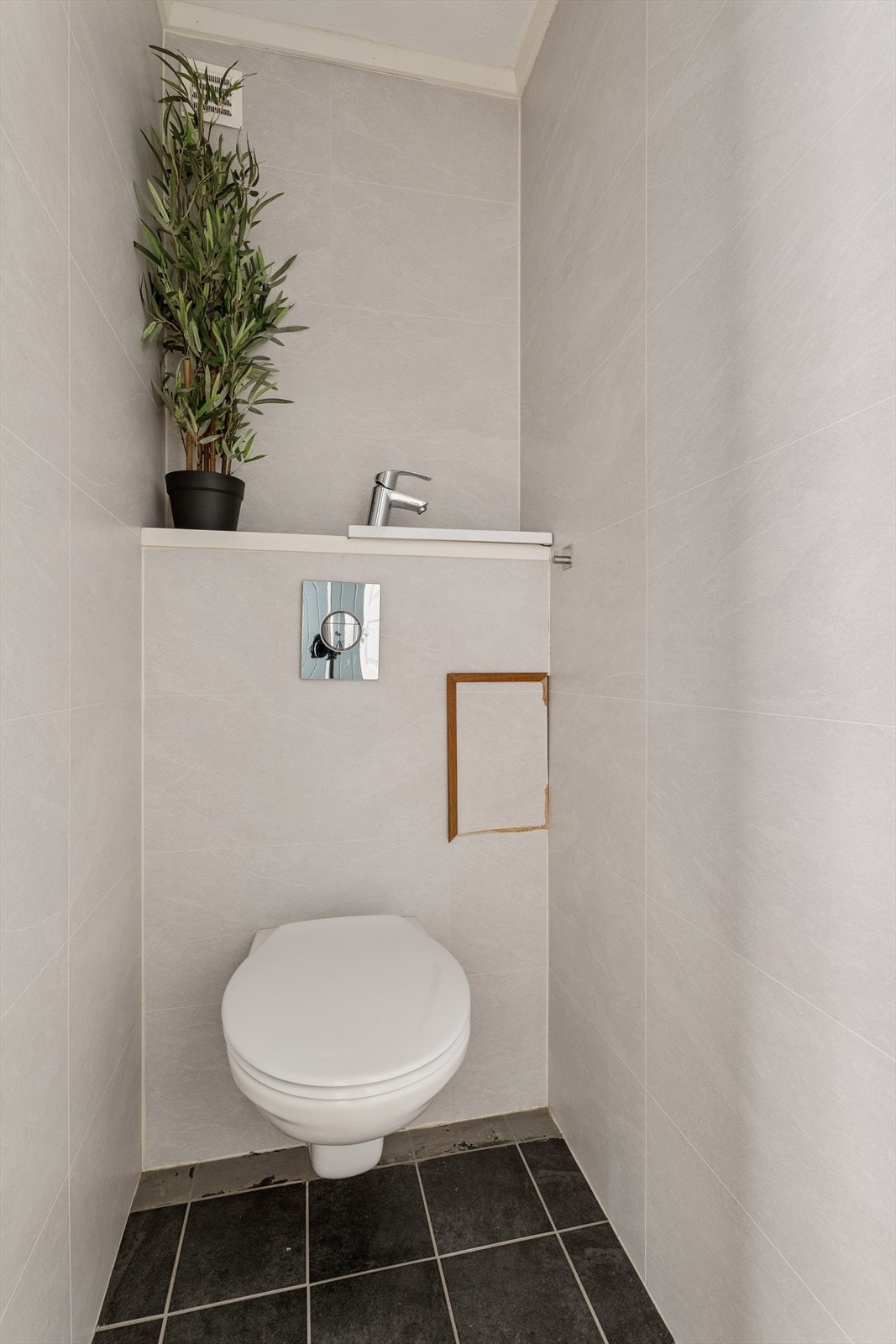 Eget toalettrom med vegghengt toalett, flislagt gulv og servant. Galleribilde