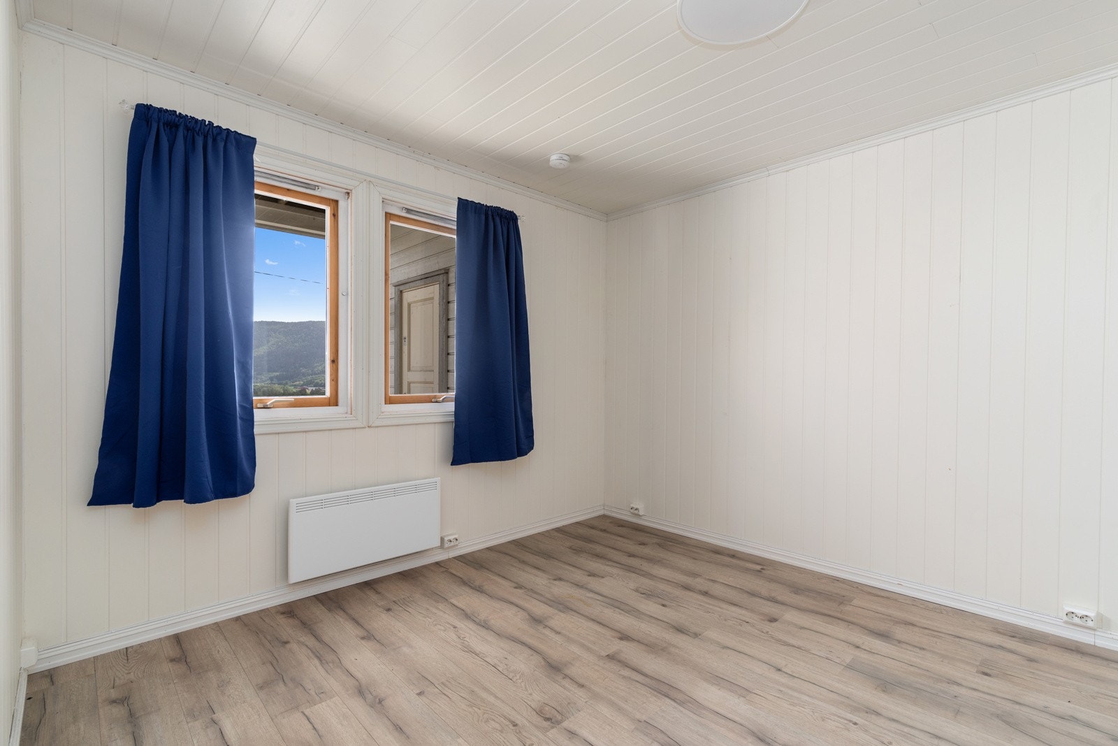 Lyst soverom i 1. etasje med laminat på gulvet og gardrobeløsning langs veggen. Panelovn på veggen. Galleribilde