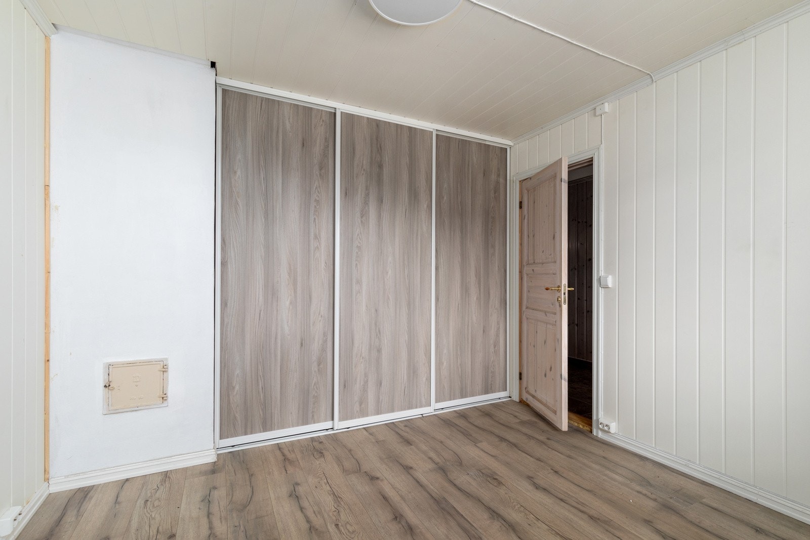 Lyst soverom i 1. etasje med laminat på gulvet og gardrobeløsning langs veggen. Panelovn på vegg. Galleribilde